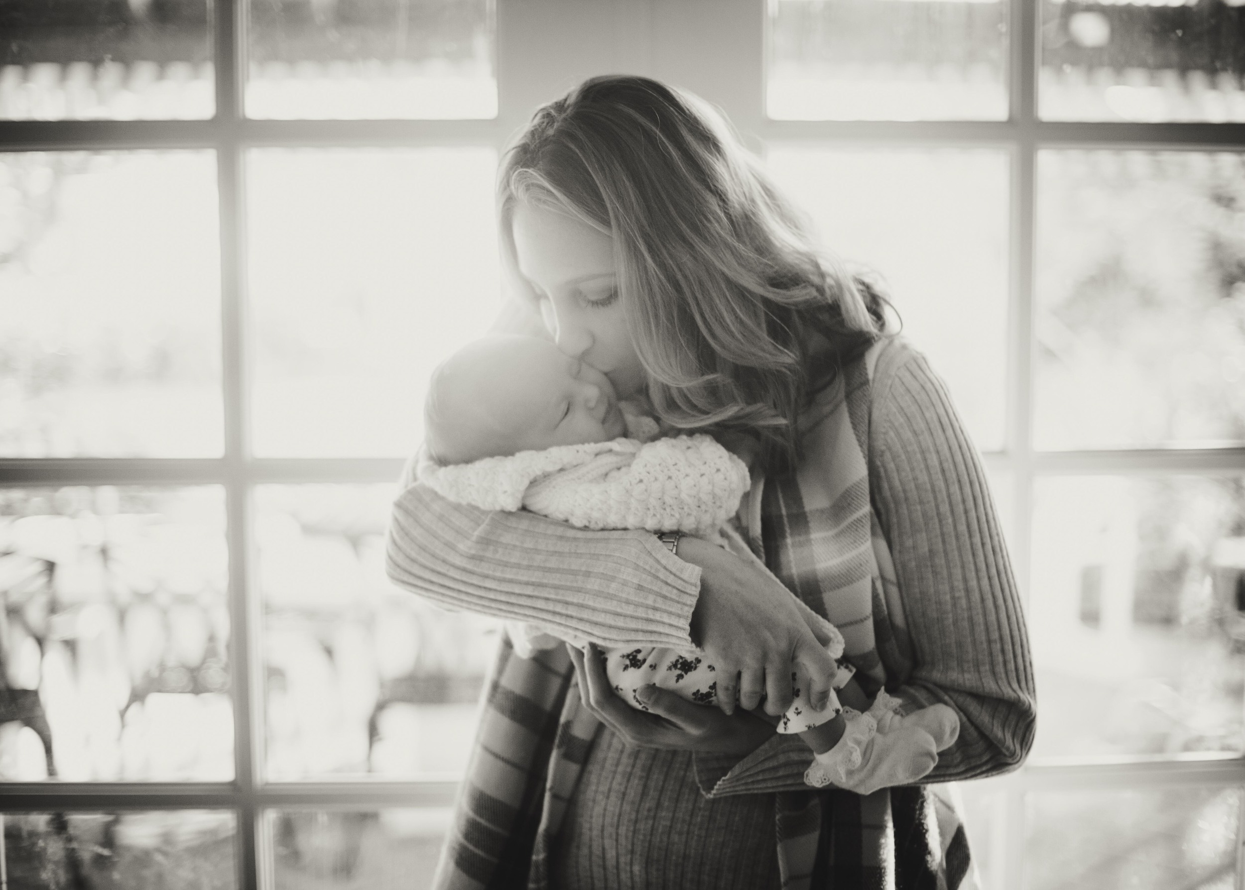 woman kissing newborn baby's forehead