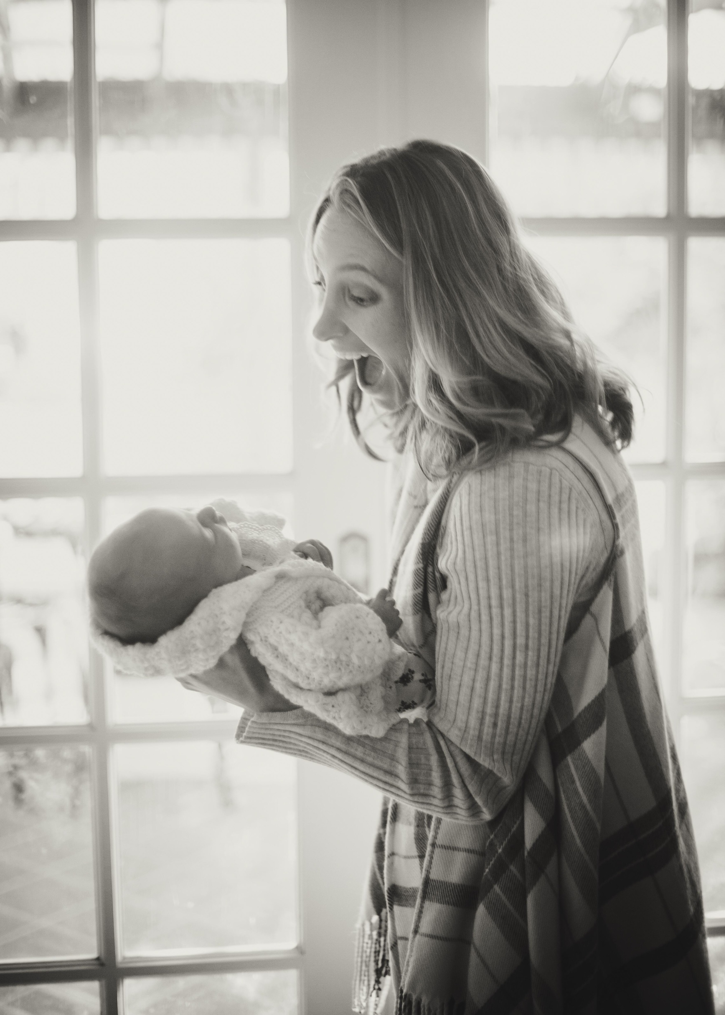 woman laughing looking at newborn baby