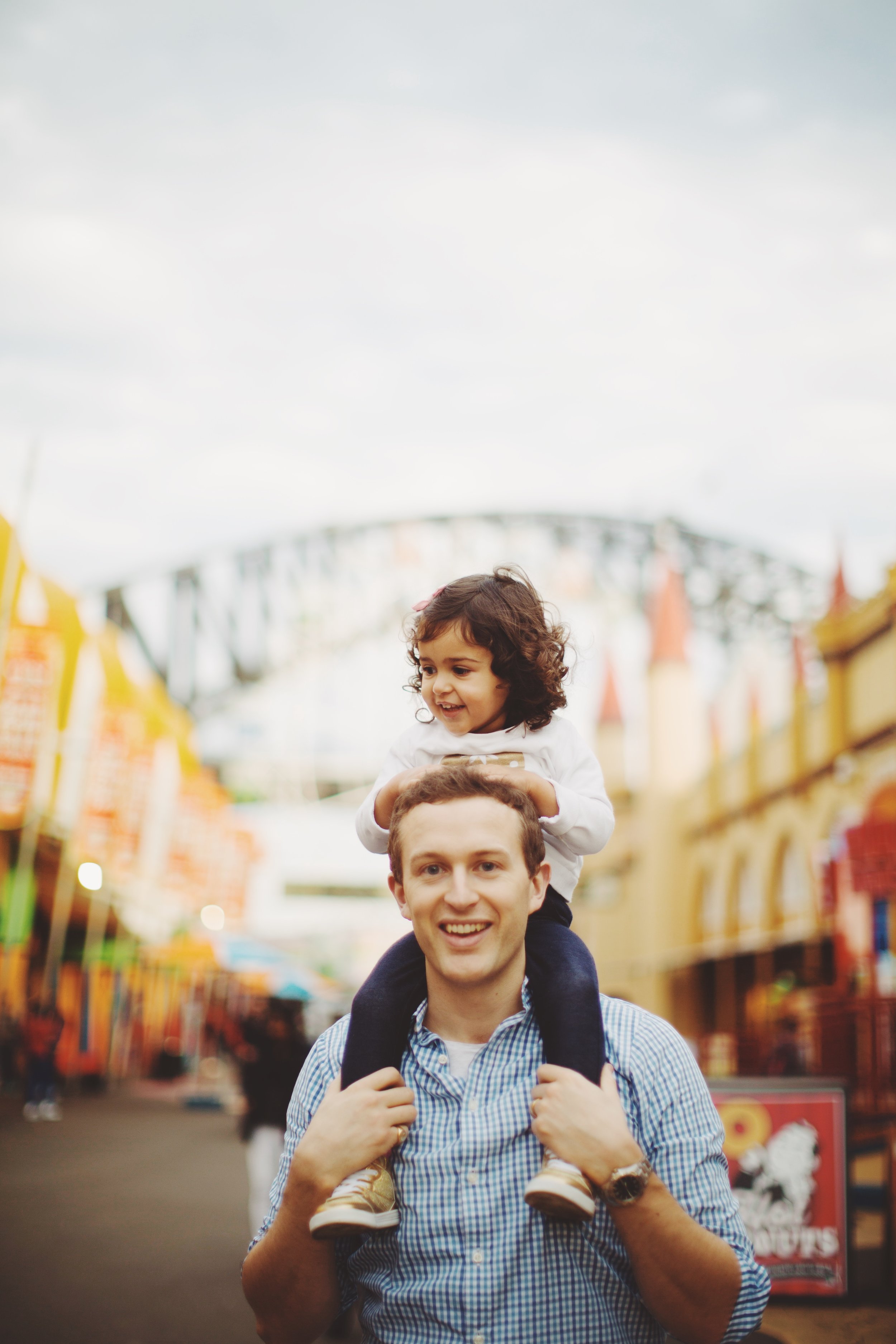 girl sits on fathers shoulders at luna park in sydney