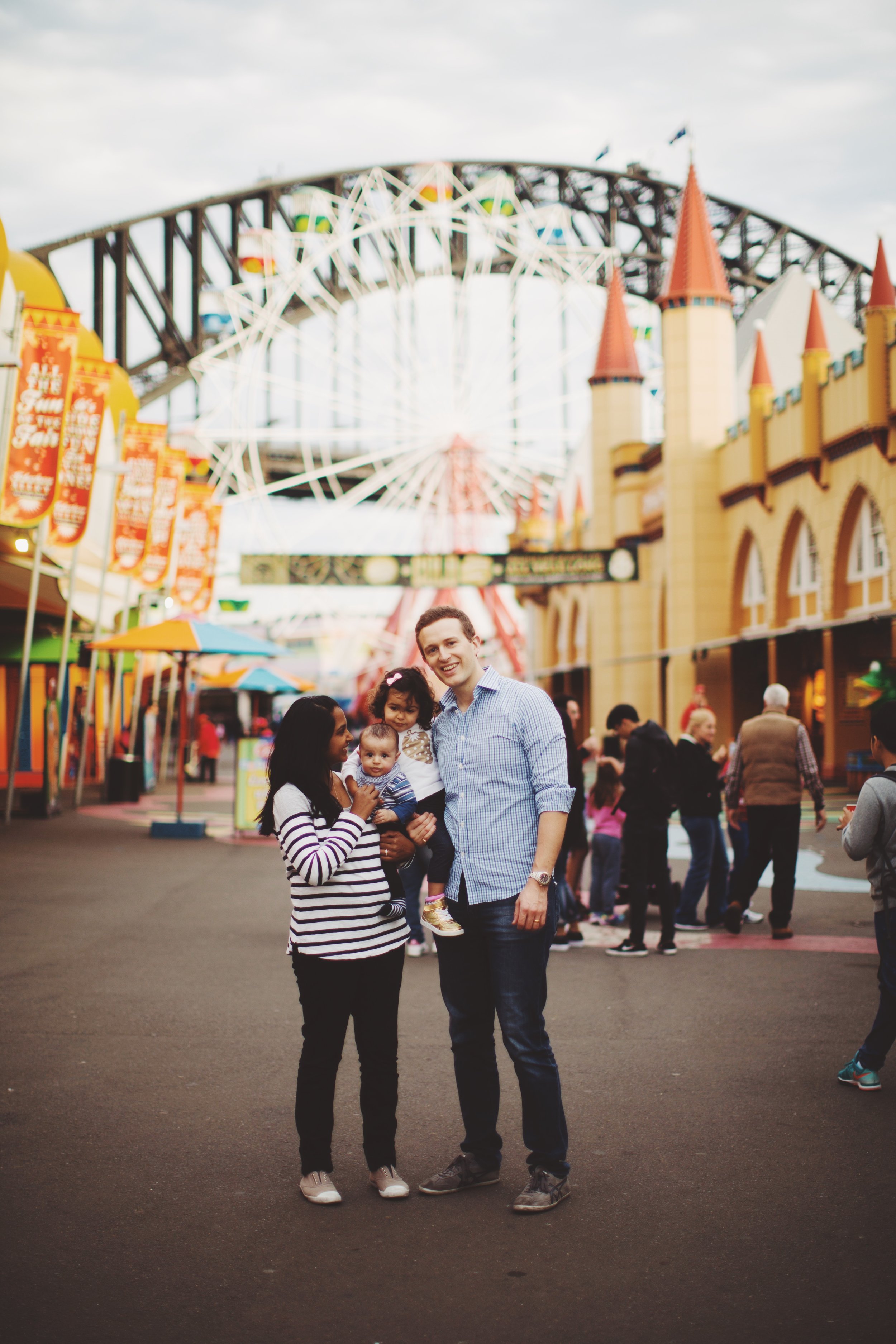 family of four stand at luna park in syndey