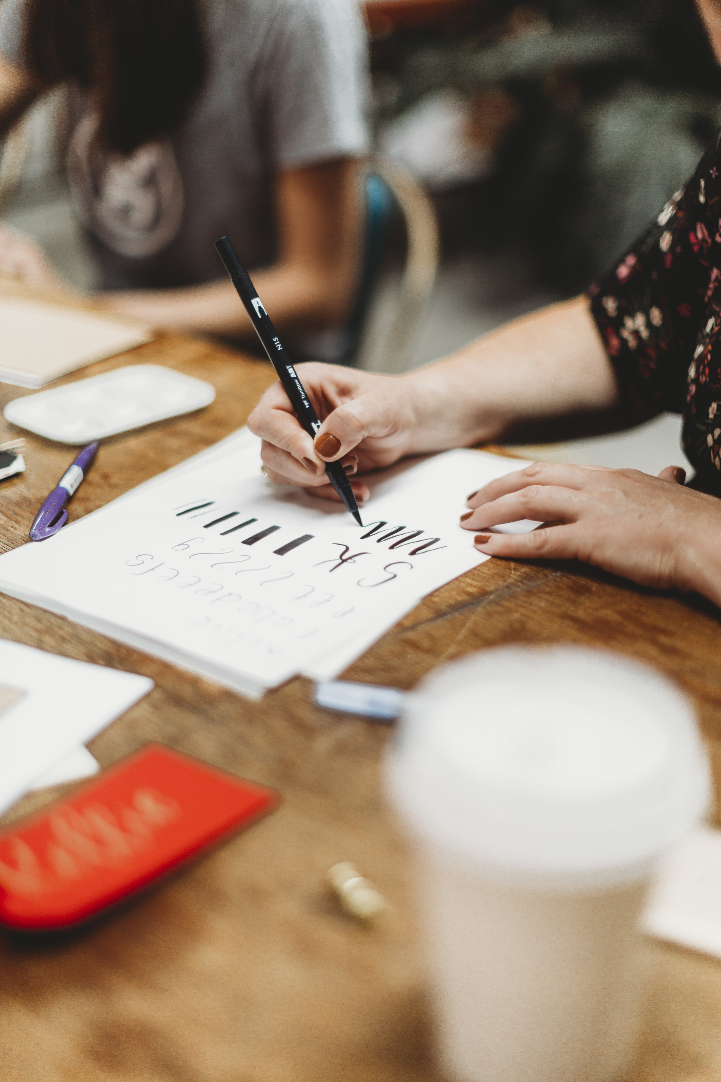 Woman doing calligraphy on white paper with black ink