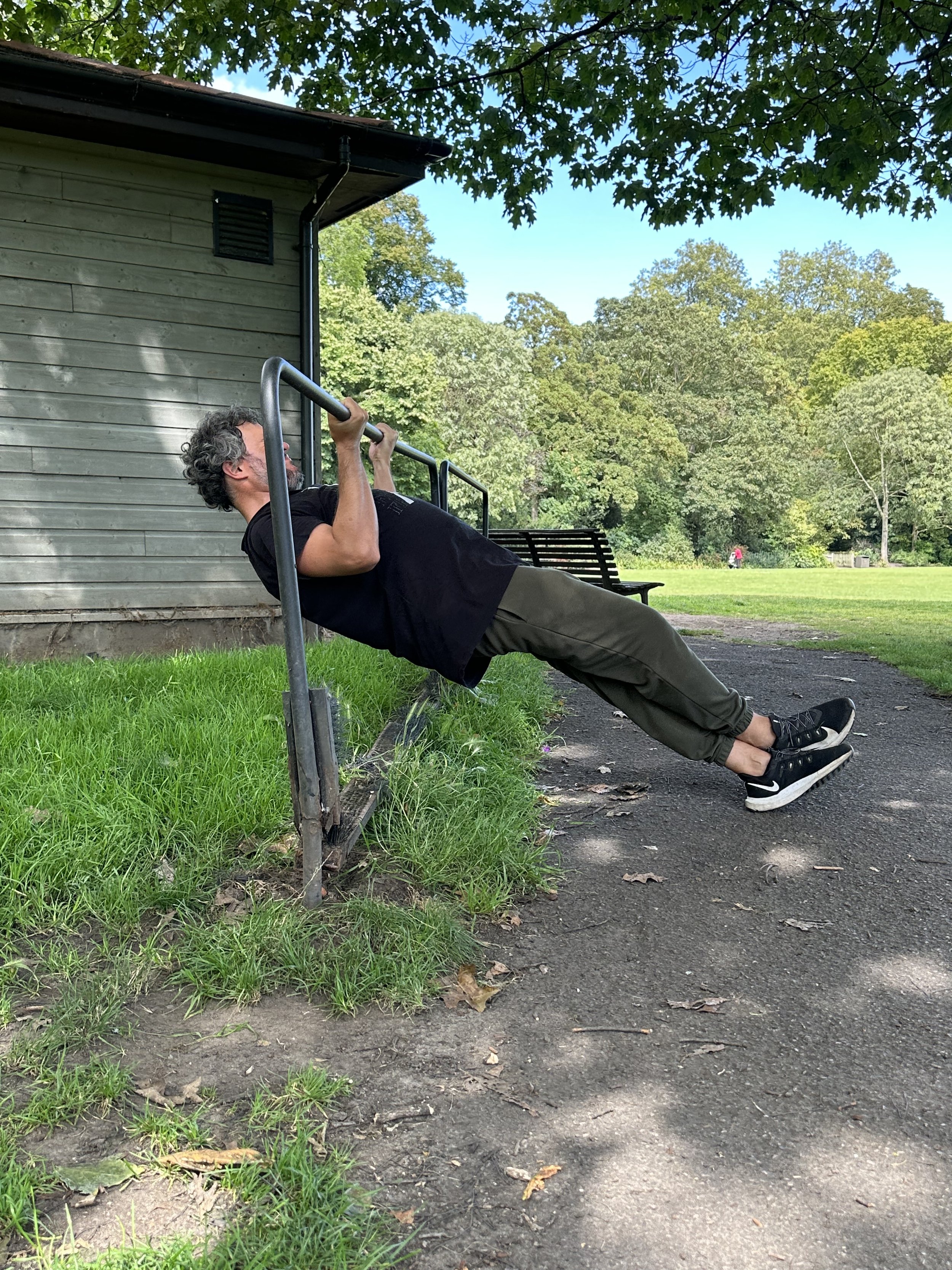 Client performing an incline row on a park bench in Battersea Park with mobile personal trainer Zara Smalley