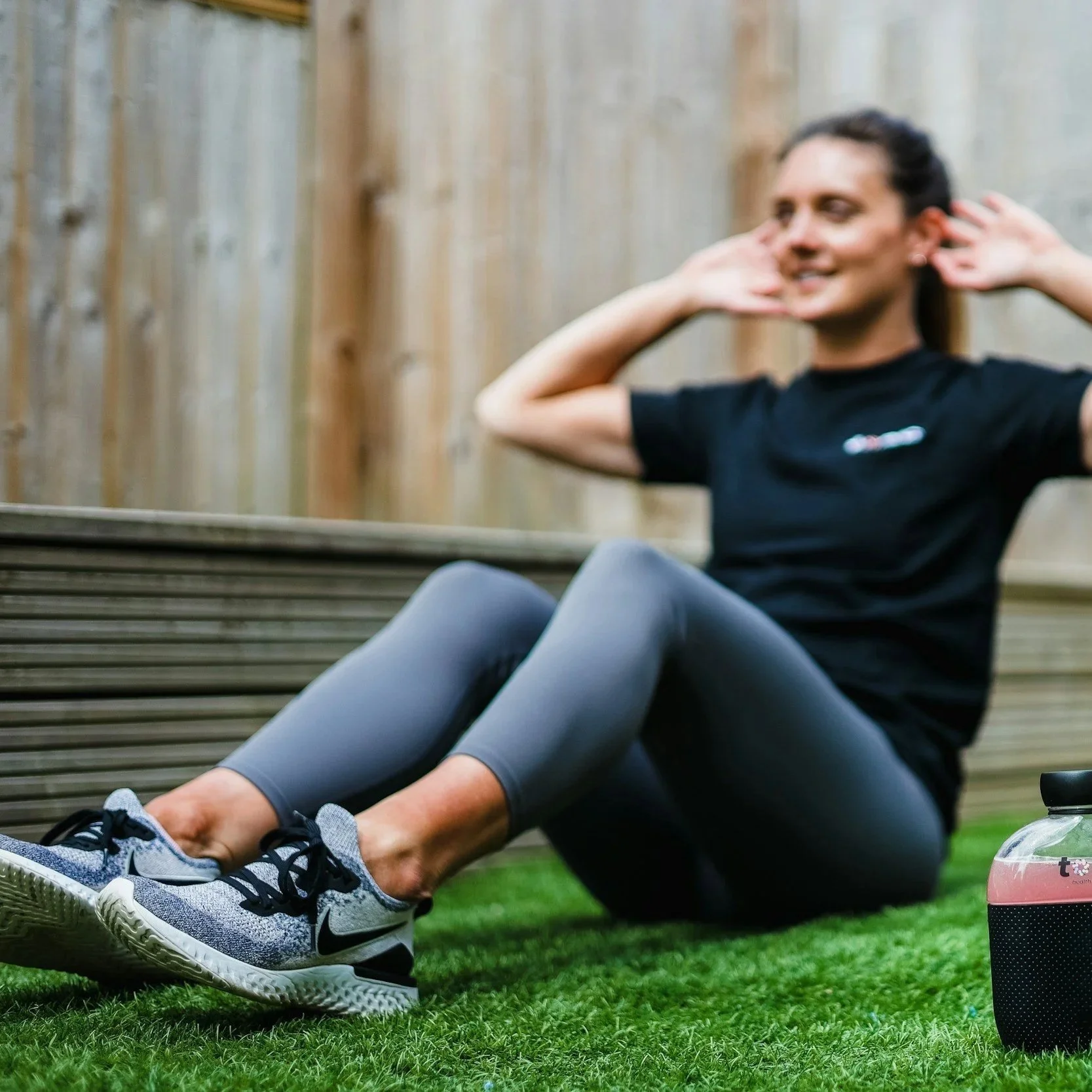 Man doing outdoor sit-ups on a mat in a Nine Elms SW8 park with modern apartment buildings in the background — personal training sessions in local green spaces