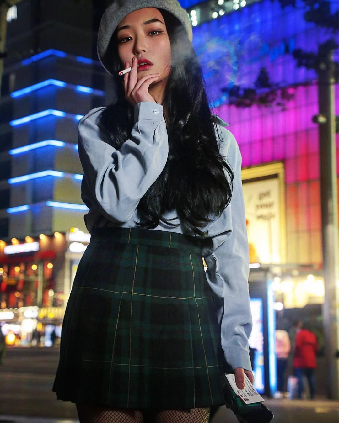 Inpromptu street fashion model So-hee HYEON is lit with a studio umbrella in front of the bright lights and bustle of the main strip in the Dongdaemun fashion district of Seoul, photographed my Michael W. Hurt. 