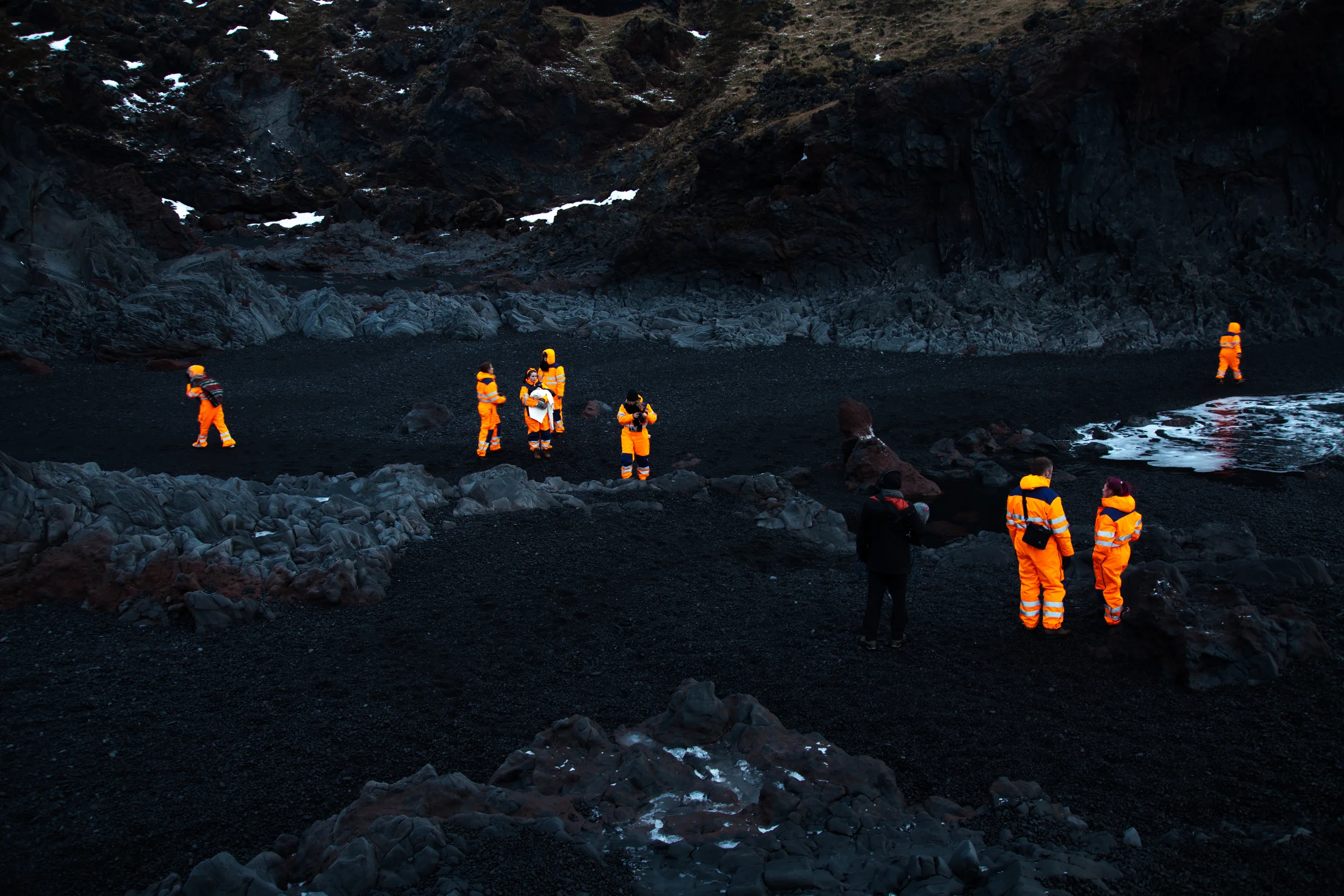 Orange suits on the black beach