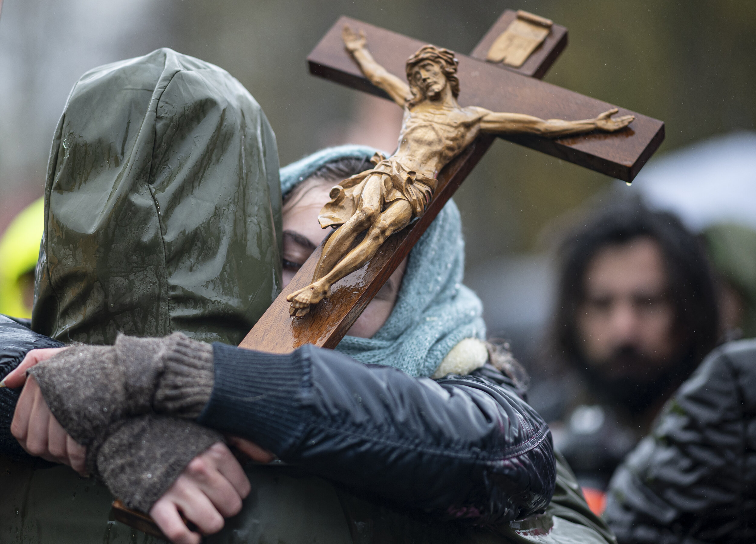  Auf einer Demonstration gegen Corona-Einschränkungen hält eine Frau ein Kreuz in der Hand, während sie ihre Begleitung umarmt. 