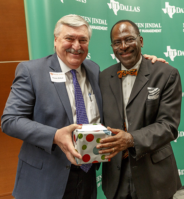 Dr. Hasan Pirkul (left), dean of the Naveen Jindal School of Management, presents a gift to Dr. David L. Ford Jr. at a recent retirement celebration. After 42 years at UT Dallas, Ford will retire Aug. 31.