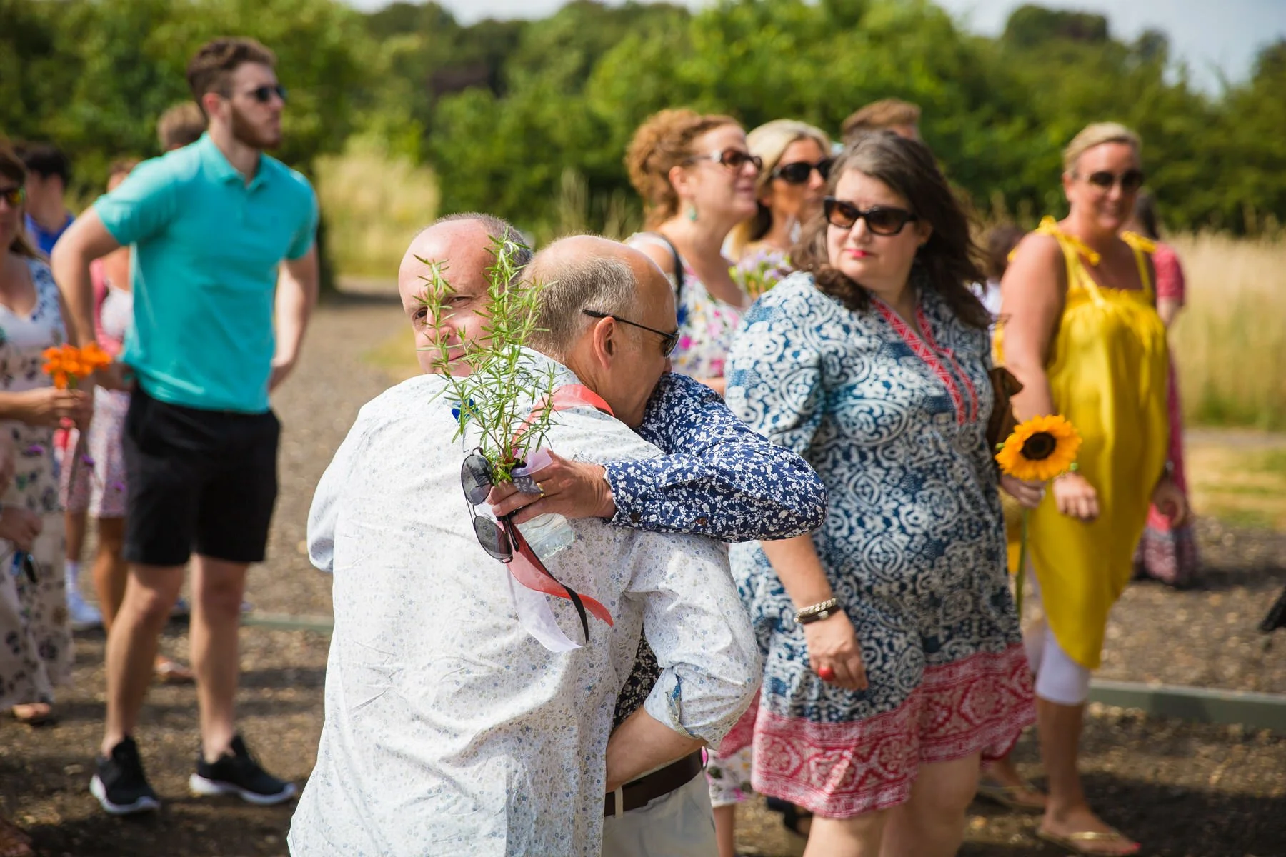 Guests arriving and greeting each other inside the glass pavilion at Clandon Wood natural burial ground in Surrey.