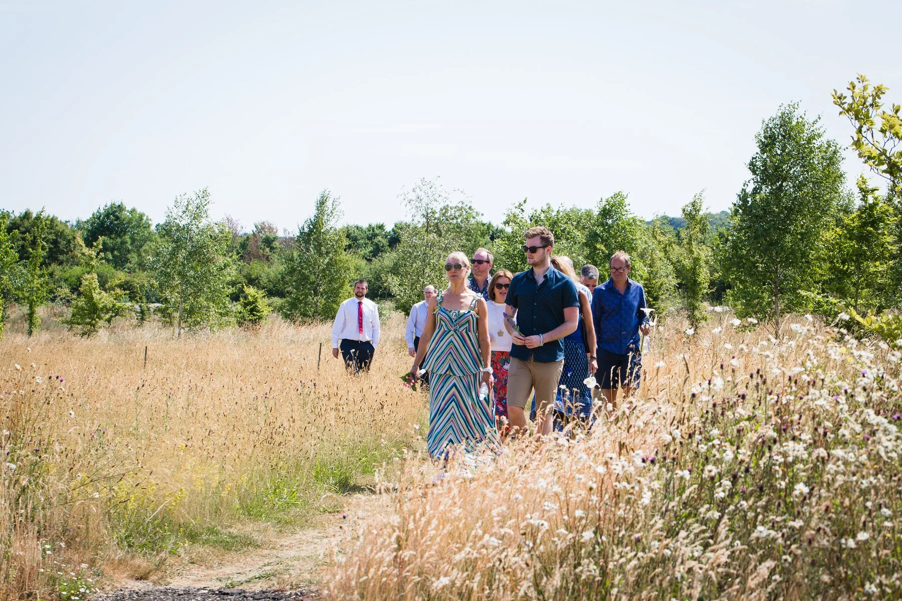 Guests arriving and greeting each other inside the glass pavilion at Clandon Wood natural burial ground in Surrey.