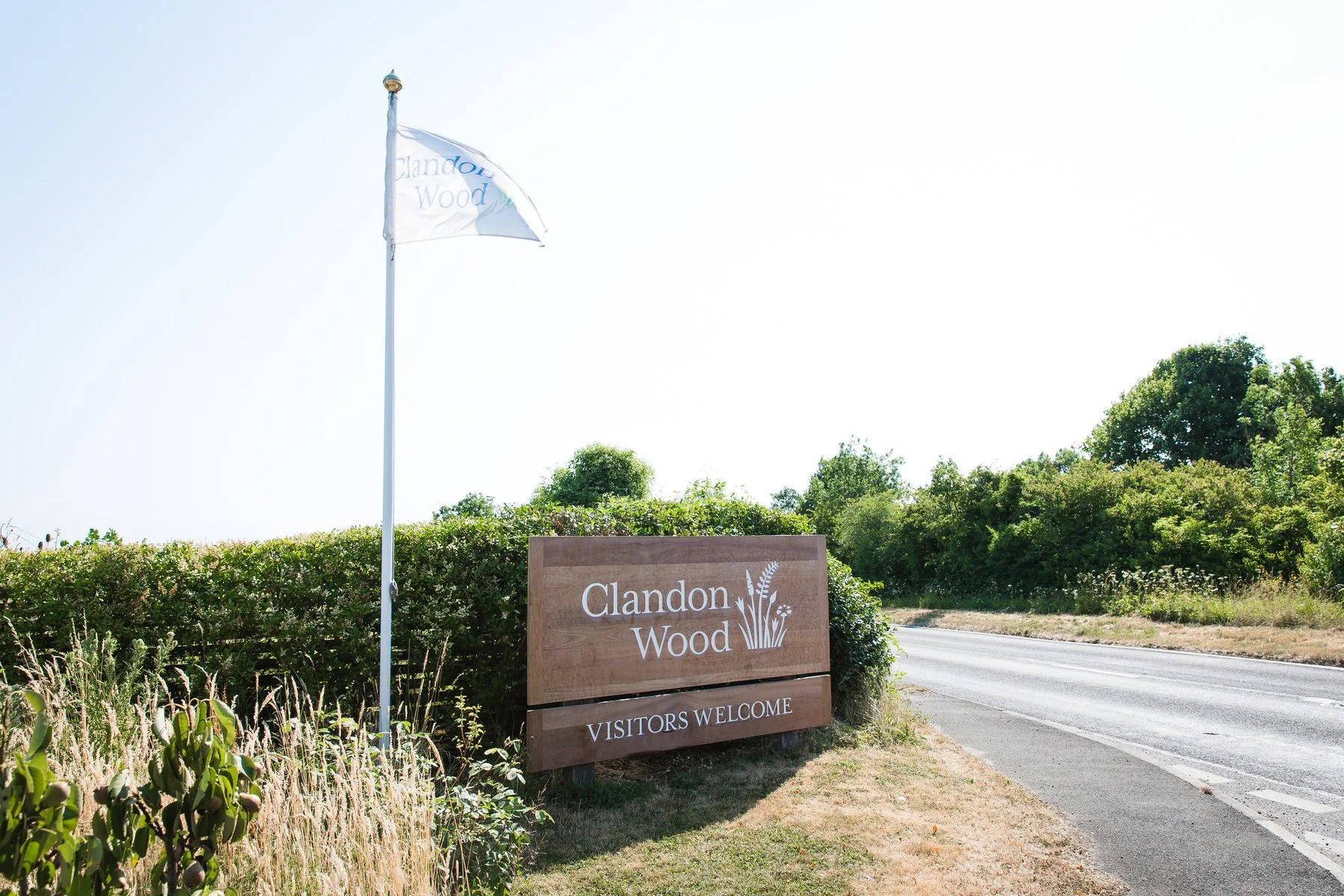 Entrance sign at Clandon Wood Natural Burial Ground in Surrey saying “Visitors welcome”.