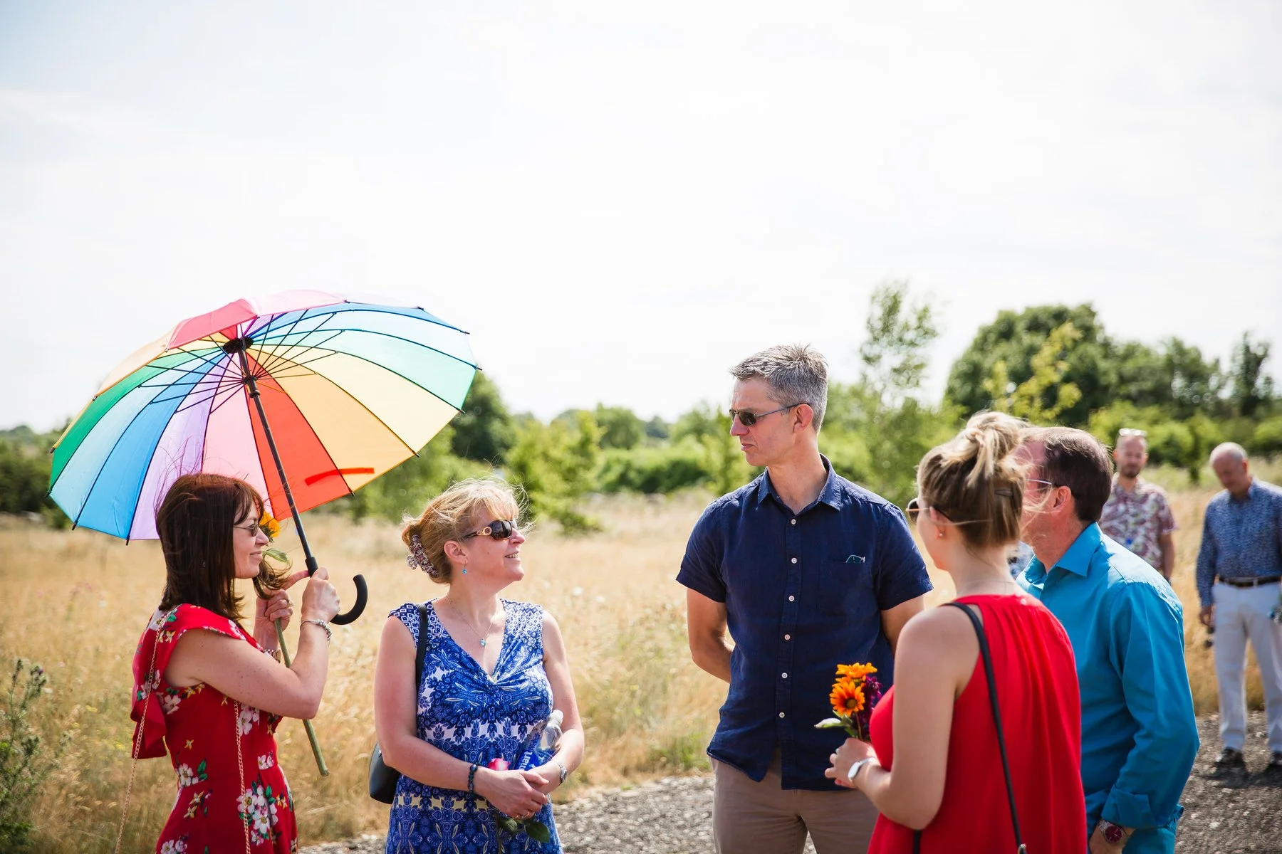 Guests arriving and greeting each other inside the glass pavilion at Clandon Wood natural burial ground in Surrey.