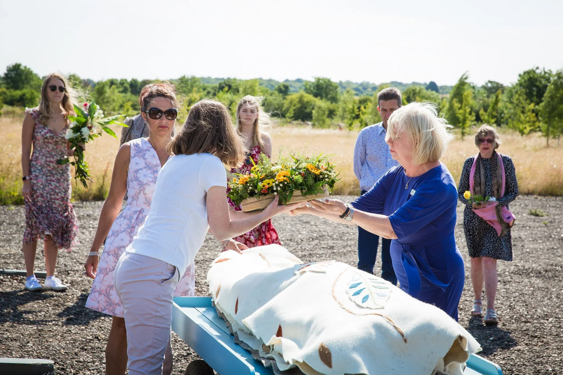 Family lifting a woollen shroud from the funeral car onto a cart at Clandon Wood natural burial ground in Surrey.