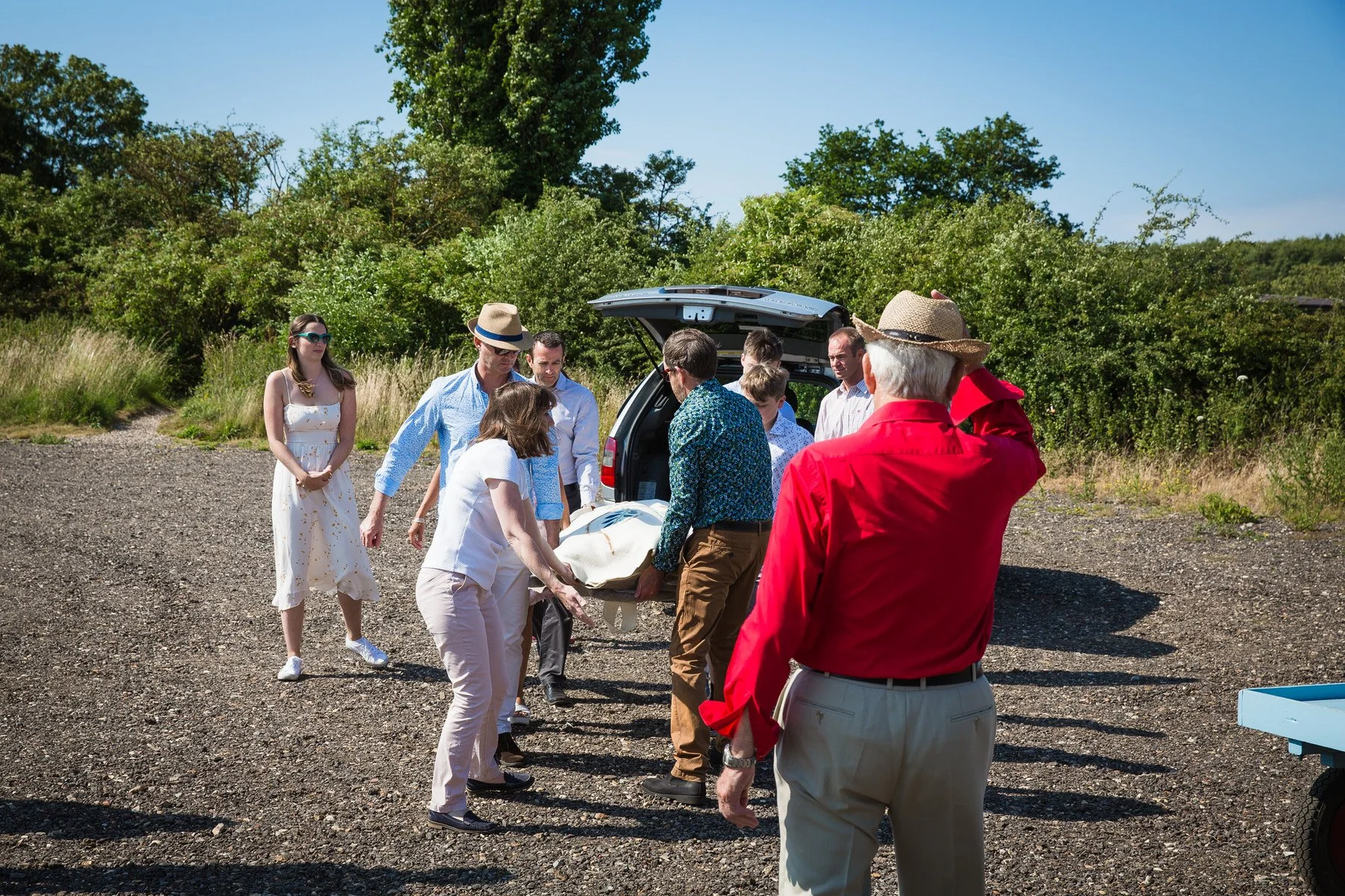 Family lifting a woollen shroud from the funeral car onto a cart at Clandon Wood natural burial ground in Surrey.
