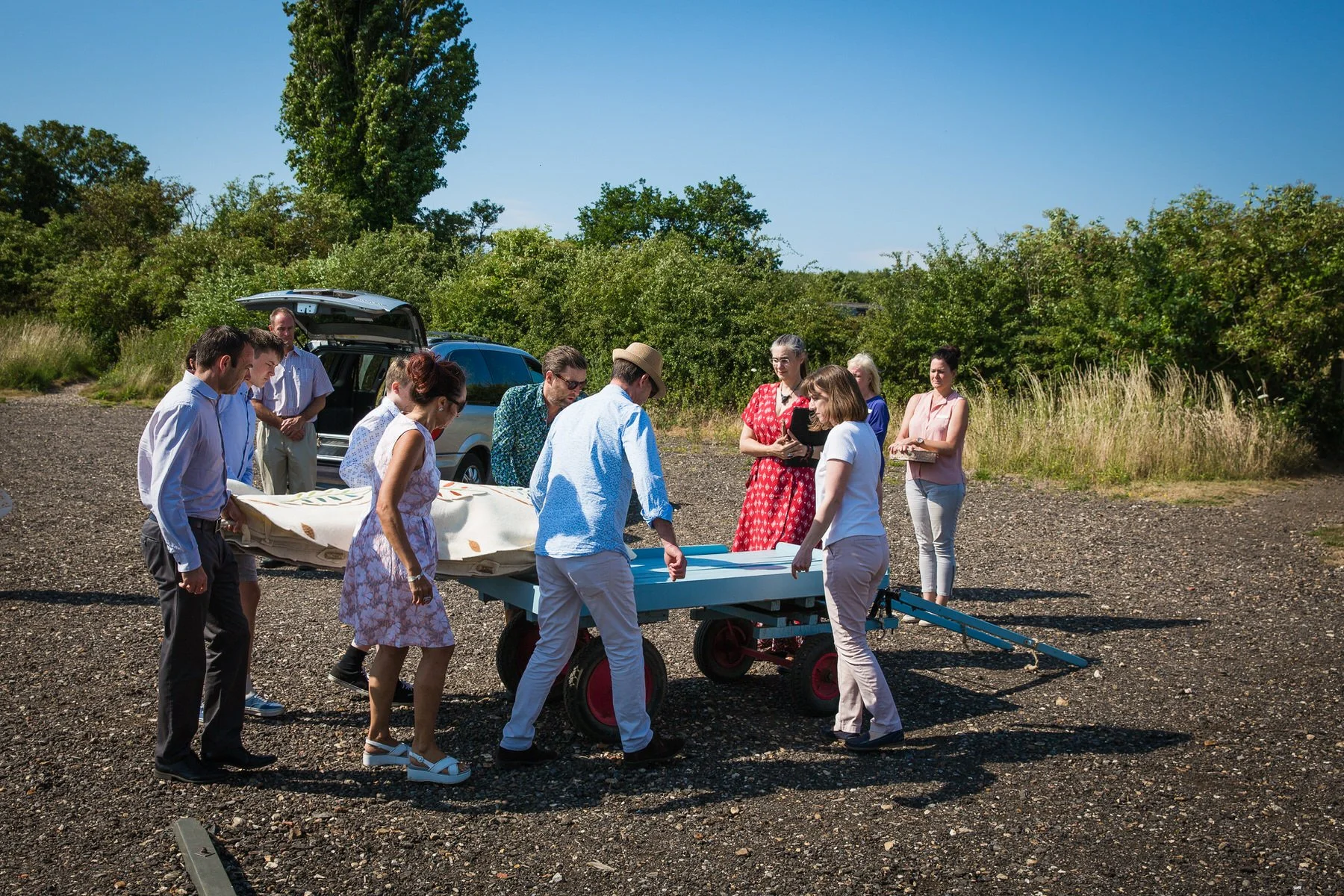 Family lifting a woollen shroud from the funeral car onto a cart at Clandon Wood natural burial ground in Surrey.