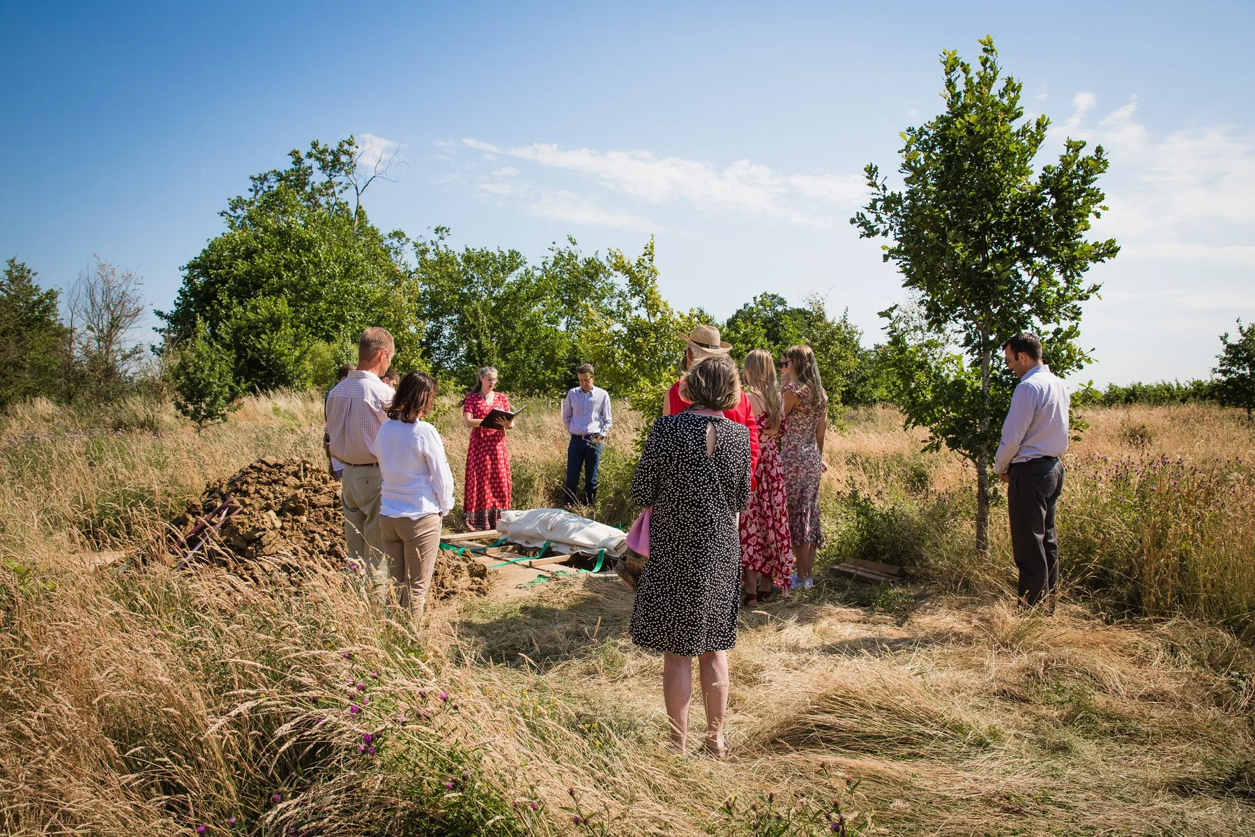 Family and friends gathered around a natural burial grave at Clandon Wood Natural Burial Ground in Surrey.