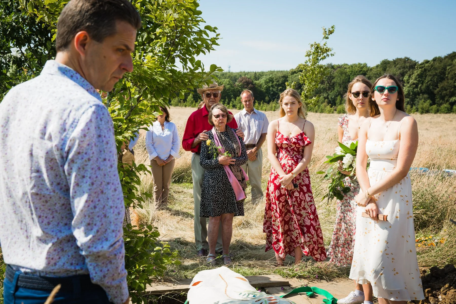 Family and friends gathered around a natural burial grave at Clandon Wood Natural Burial Ground in Surrey.