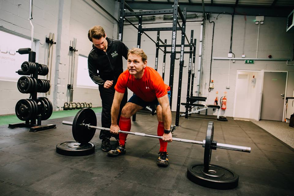 Personal trainer with client doing weights