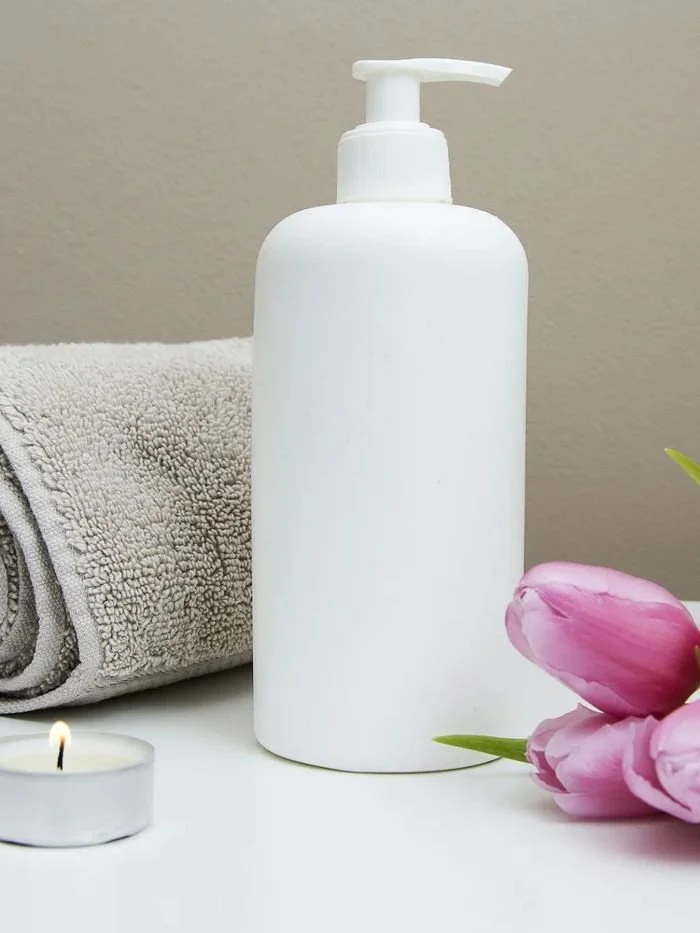 Massage oil bottle, rolled towel, tea light, and tulips