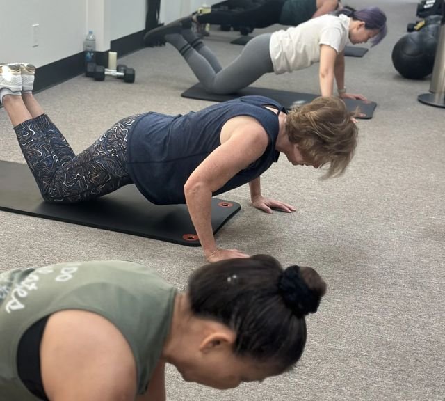 Clients doing push-ups in a Total Body Conditioning class