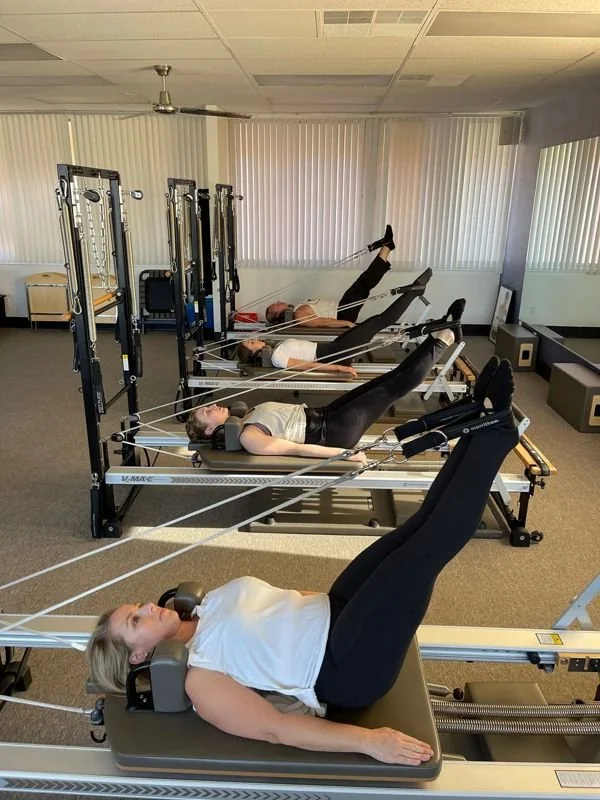 Clients doing reformer Pilates in a small group class in San Diego