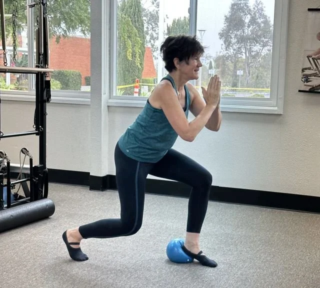 Client doing a lunge with a small prop in a mixed equipment Pilates class