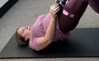 Client doing a weighted glute bridge in a strength class