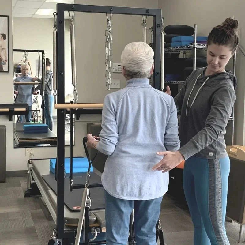 Instructor guiding a client through a private Pilates session on the tower