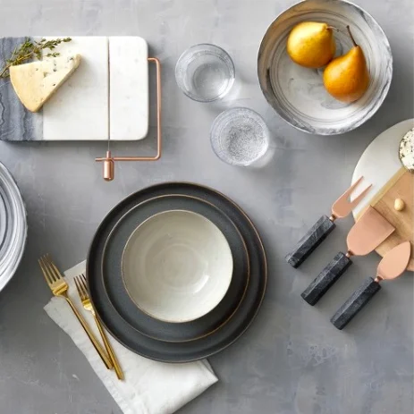 Dinnerware clockwise as shown: Marble Cheese Slicer $19.99, Porcelain Serving Bowl $16.14, Cheese Knife Set - Copper $16.99, Tiley Stoneware 16pc Set $59.99, Izon 5 pc Silverware Gold Set $19.99