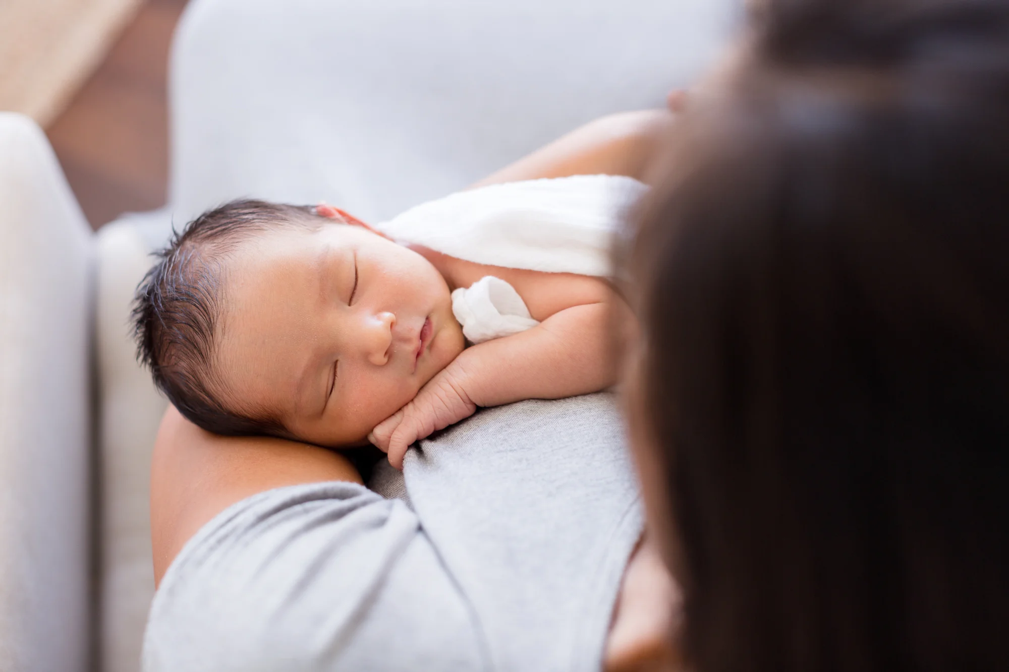 sweet sleeping newborn baby in mom’s arms