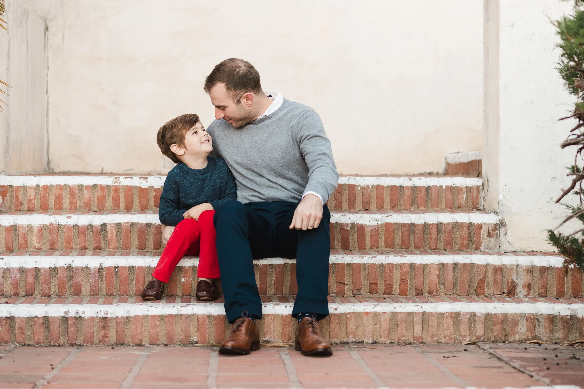 FATHER AND SON SITTING TOGETHER ON STAIRS AT SAN DIEGO’S PRESIDIO PARK