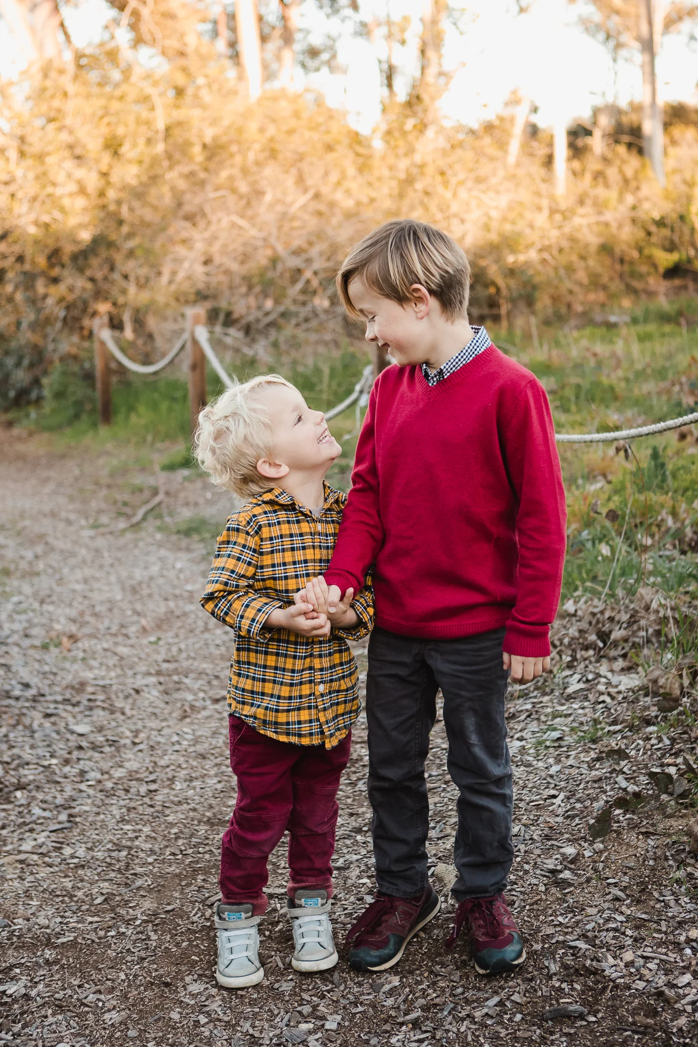 Little boys in brightly colored clothing holding hands looking at each other at San Dieguito Park in Encinitas, California. Encinitas family photographer, San Diego Family Photographer, Family photography in Southern California