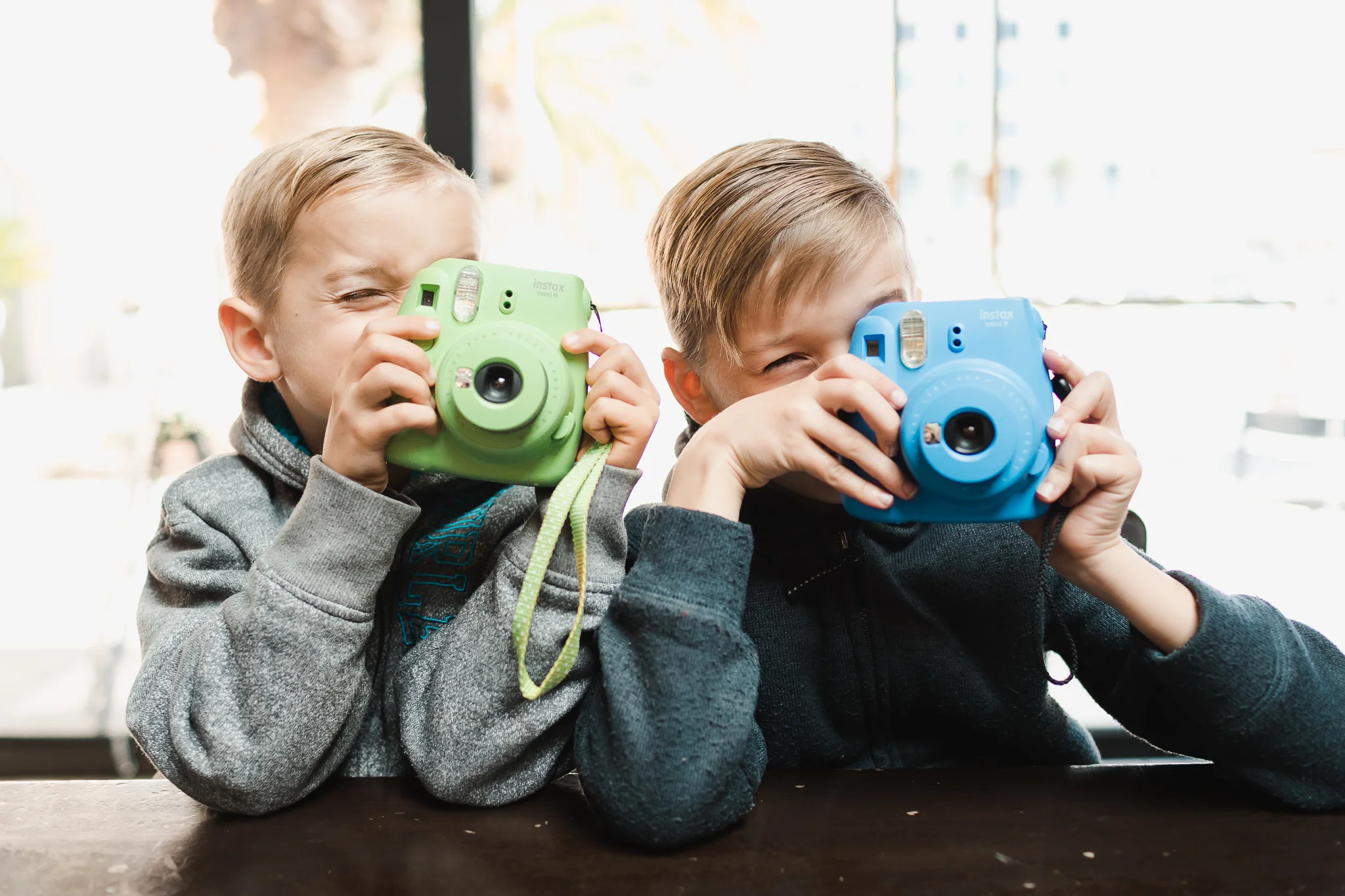 TWO BOYS HOLDING FUJI INSTAX CAMERAS UP READY TO TAKE A PHOTO