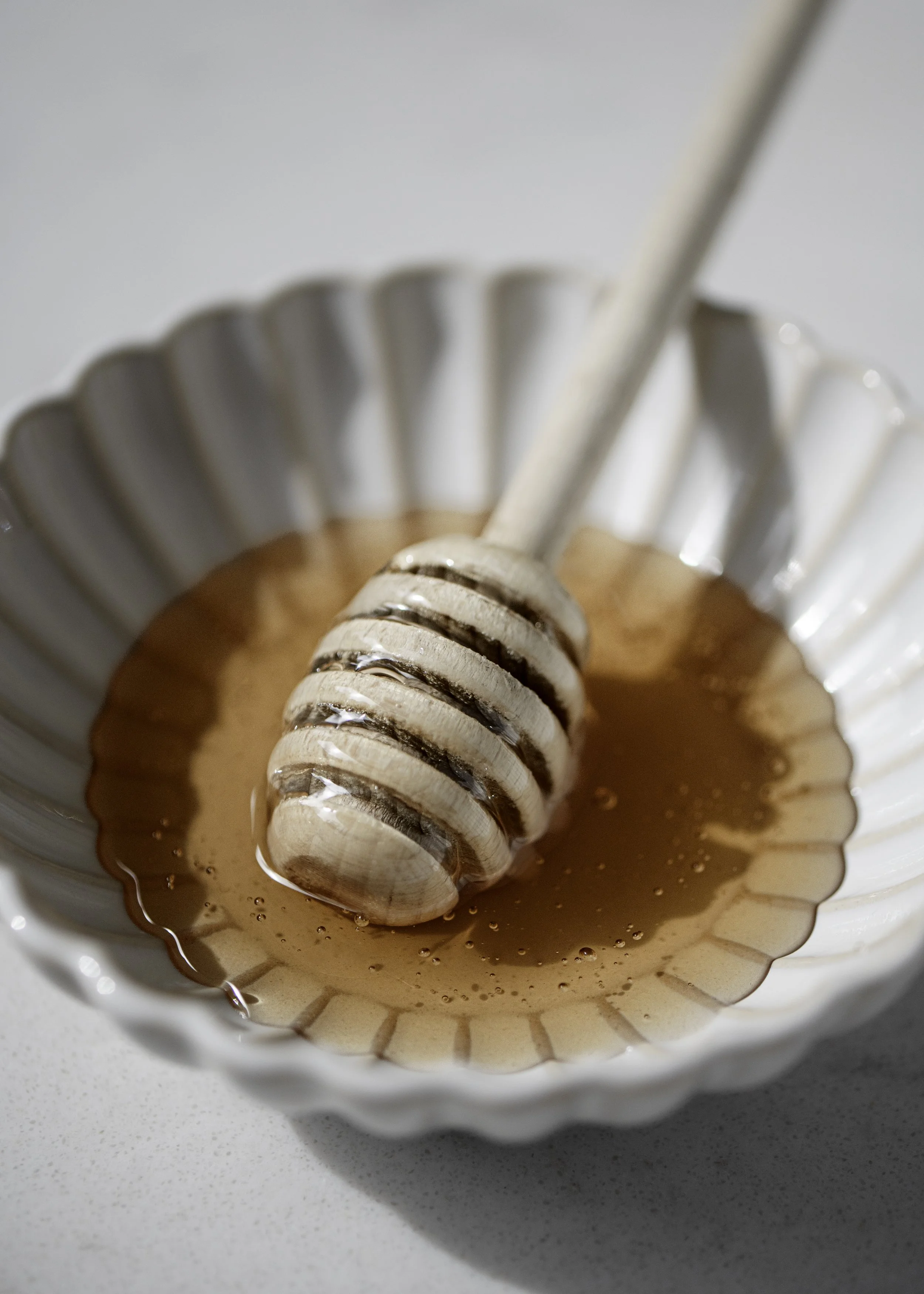 Close-up of a metal whisk stirring chocolate mixture in a white, fluted bowl on a white surface.