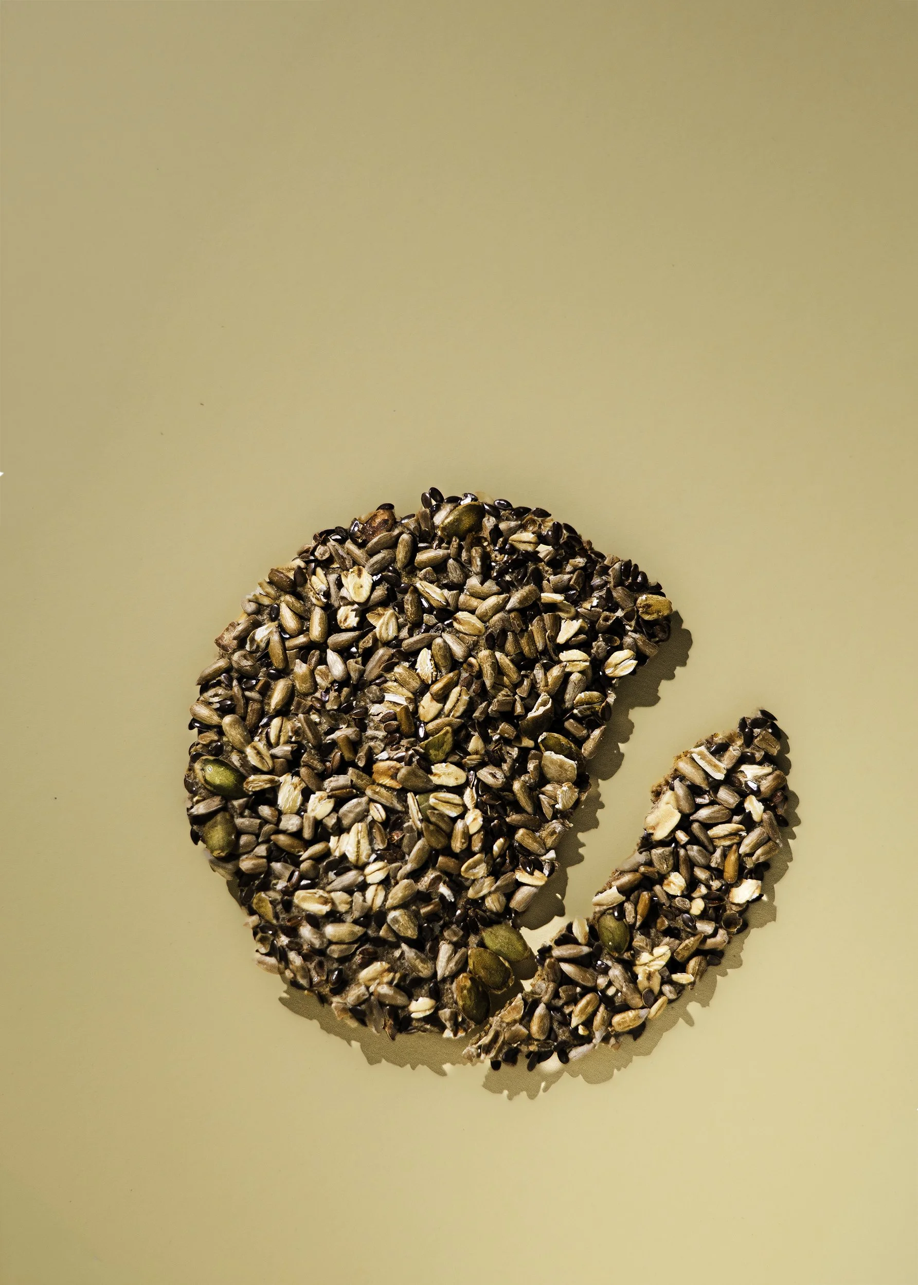 Large group of sunflower seeds forming a heart shape on a beige background.