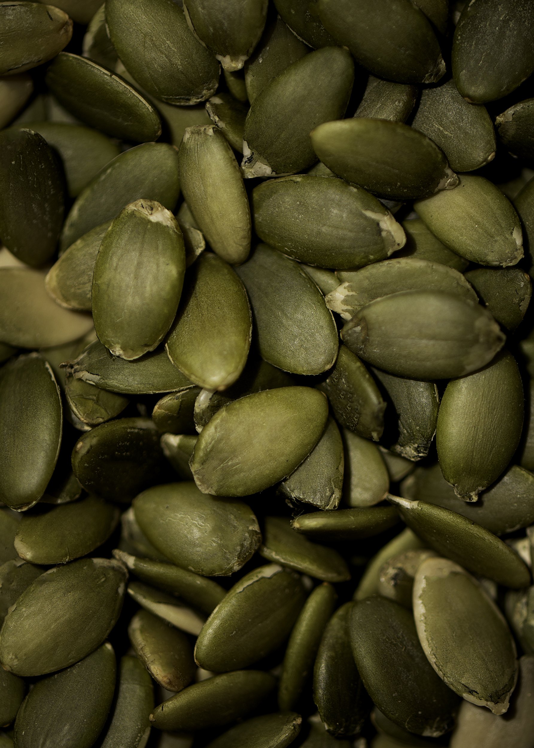 Close-up of green pumpkin seeds with slightly rough texture and outer shells.