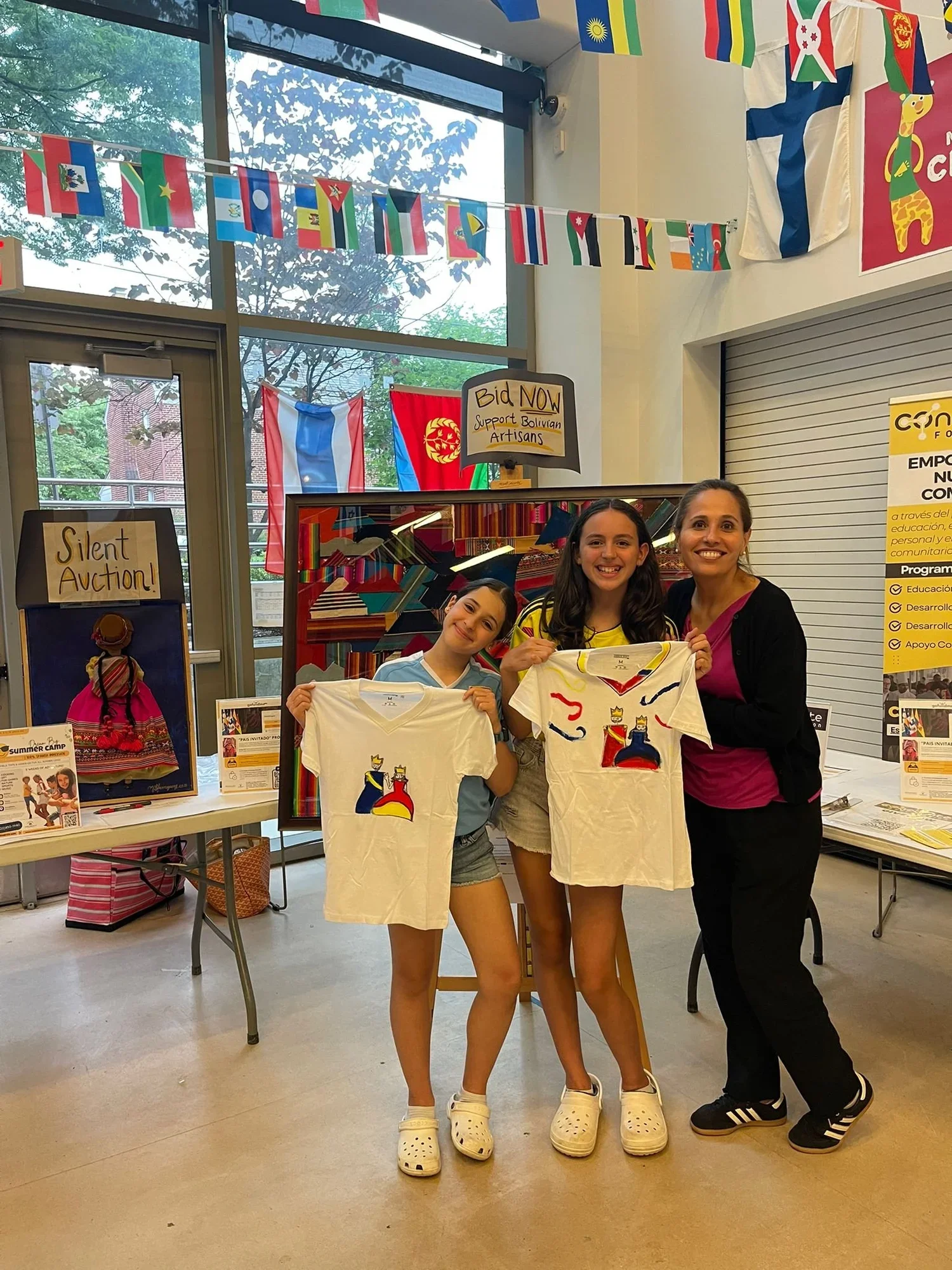 Students showing hand-painted Isabella & Ferdinand T-shirts at a cultural event