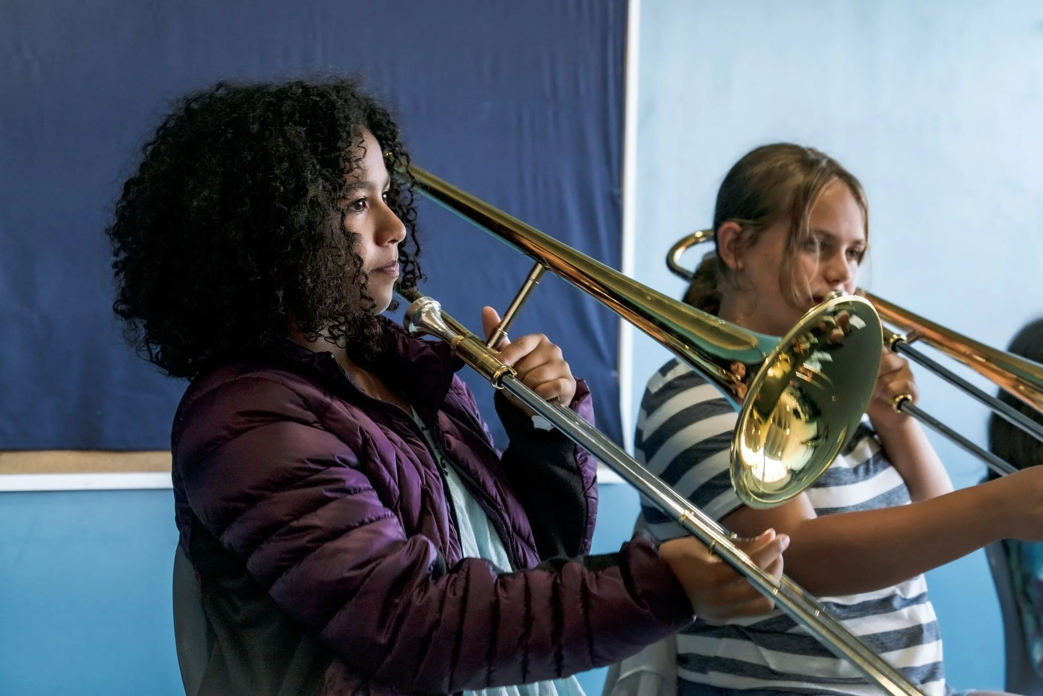seattle summer music camp with two young students holding and playing a trombone
