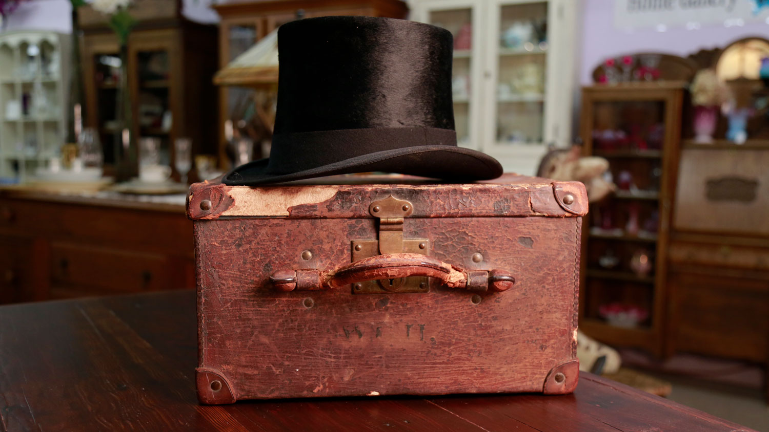  A hat box for a top hat with the worn initials W.G.H. is shown with a collectible black beaver top hat. 