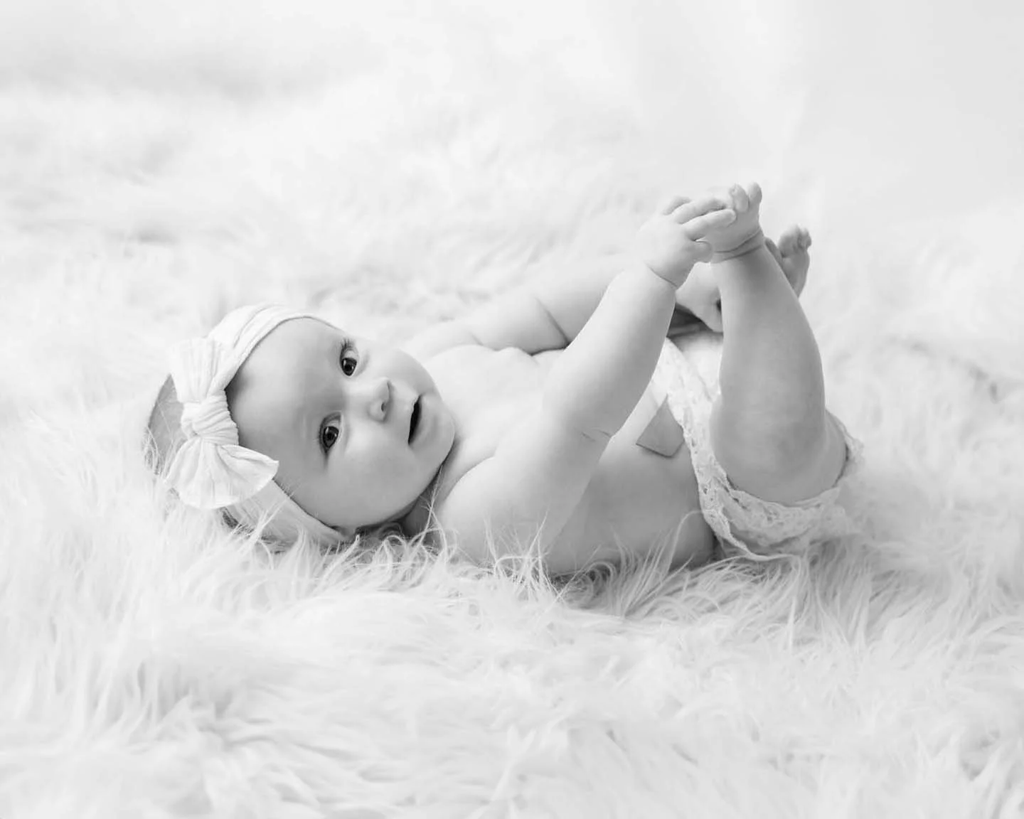 Baby milestone holding toes on back smiling