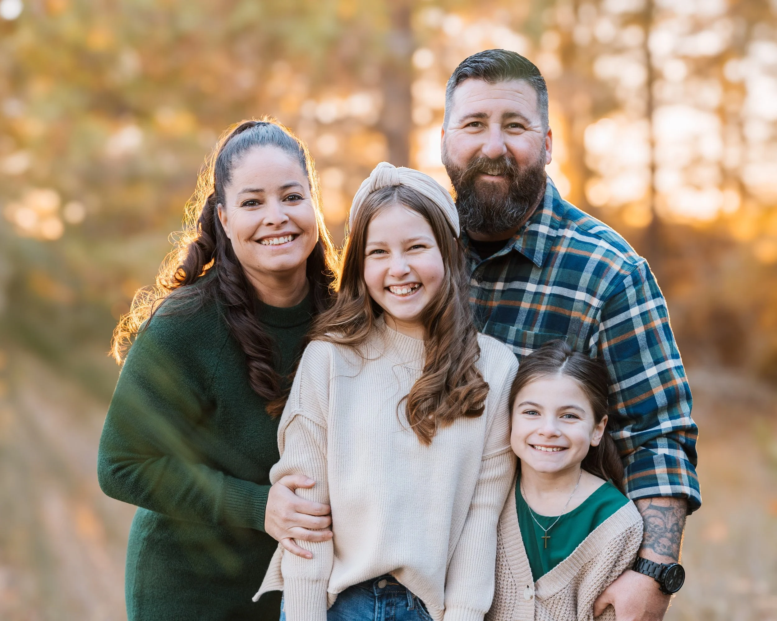 FamilyOfFourSmilingOutsideInGoldenLight