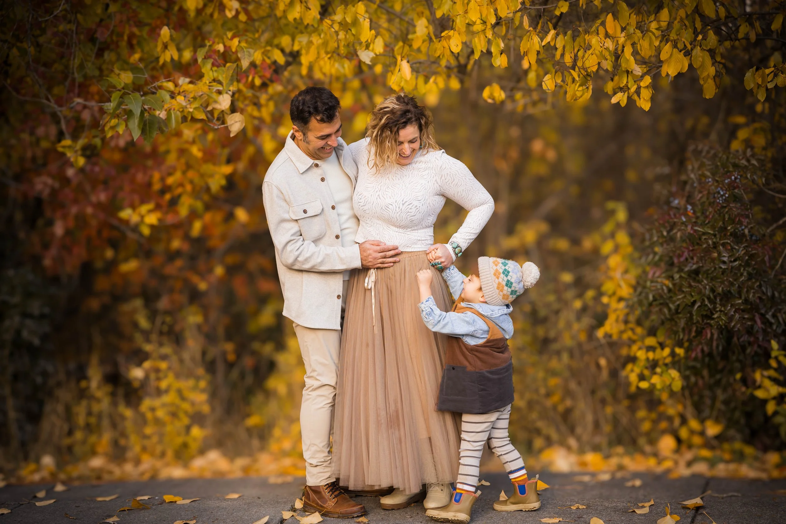 Family walking hand in hand beneath golden autumn trees during a fall family photography session at Blackwell in Coeur d'Alene, Idaho.
