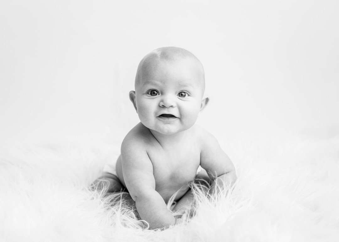 Baby milestone holding toes on back smiling