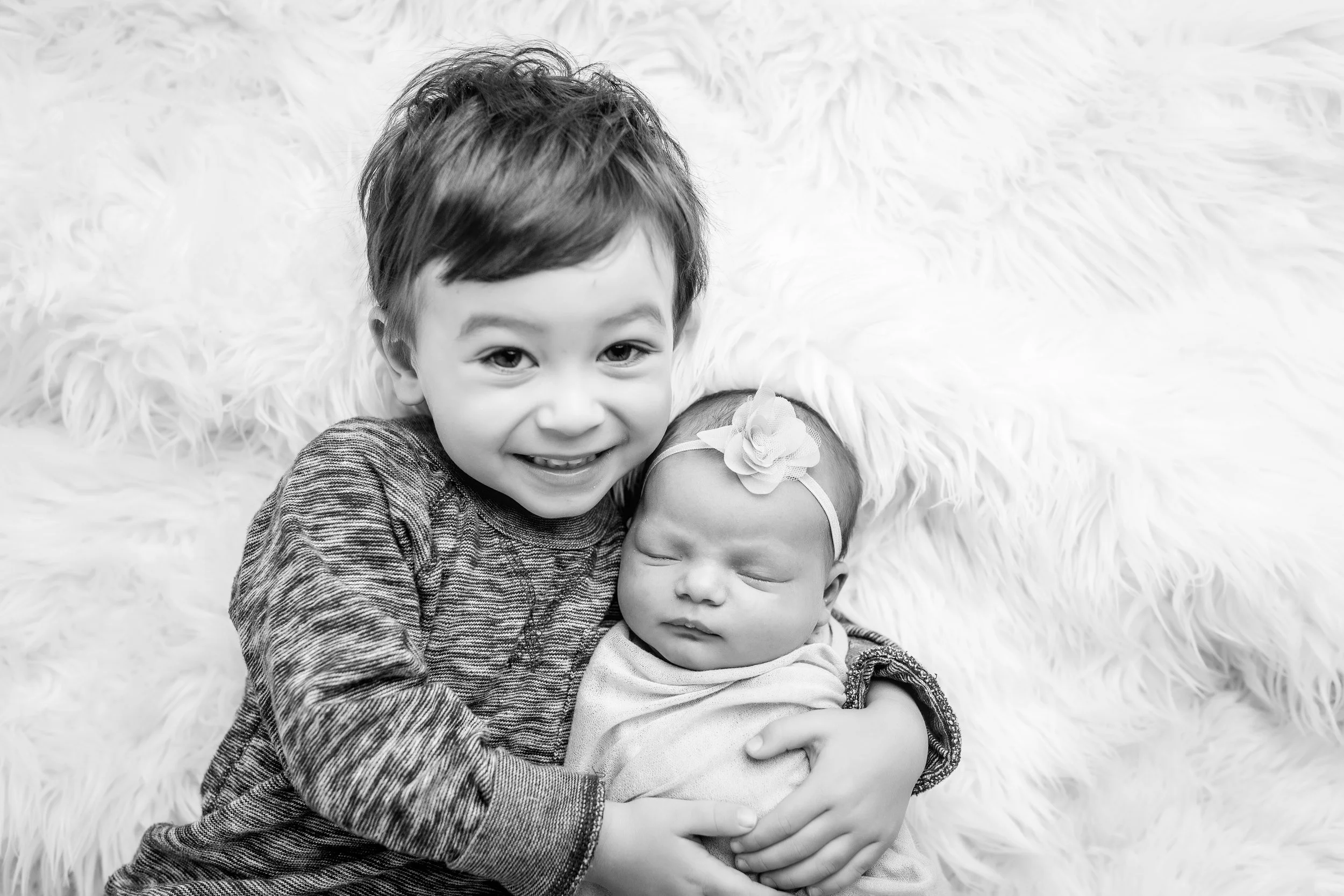 big brother siblings with newborn session hugging black and white in studio in coeur d'alene