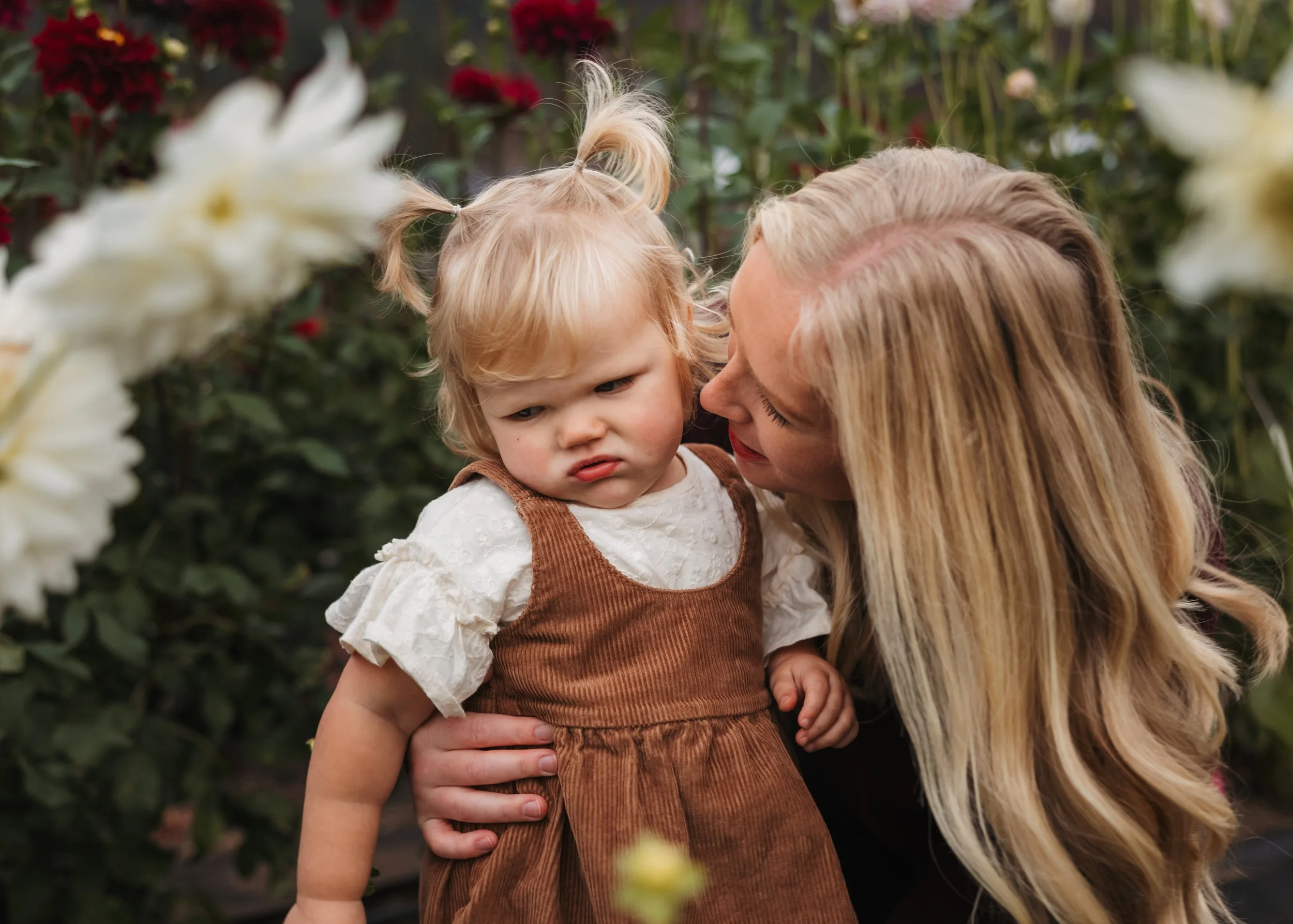 Close-up of mom comforting young child in outdoor garden setting with soft natural light