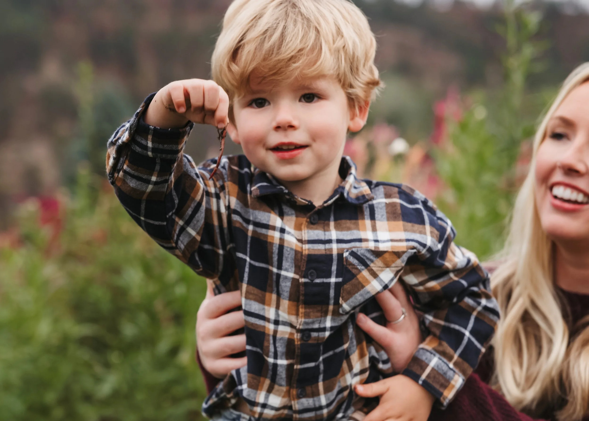 Family photo session in natural garden with worm in young boys hand