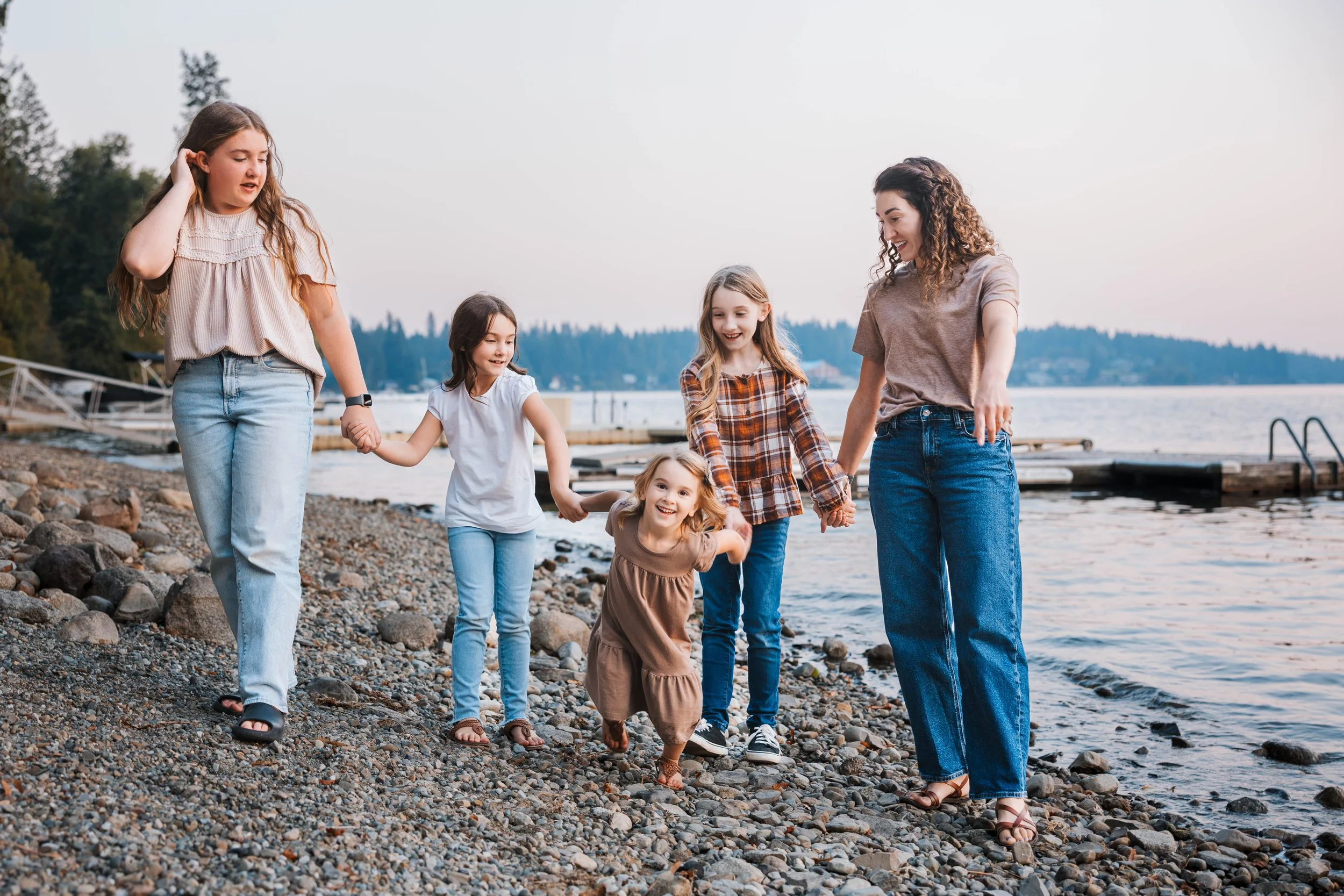 Family walking along lakeshore in Coeur d’Alene Idaho during sunset family photography session with children and mother