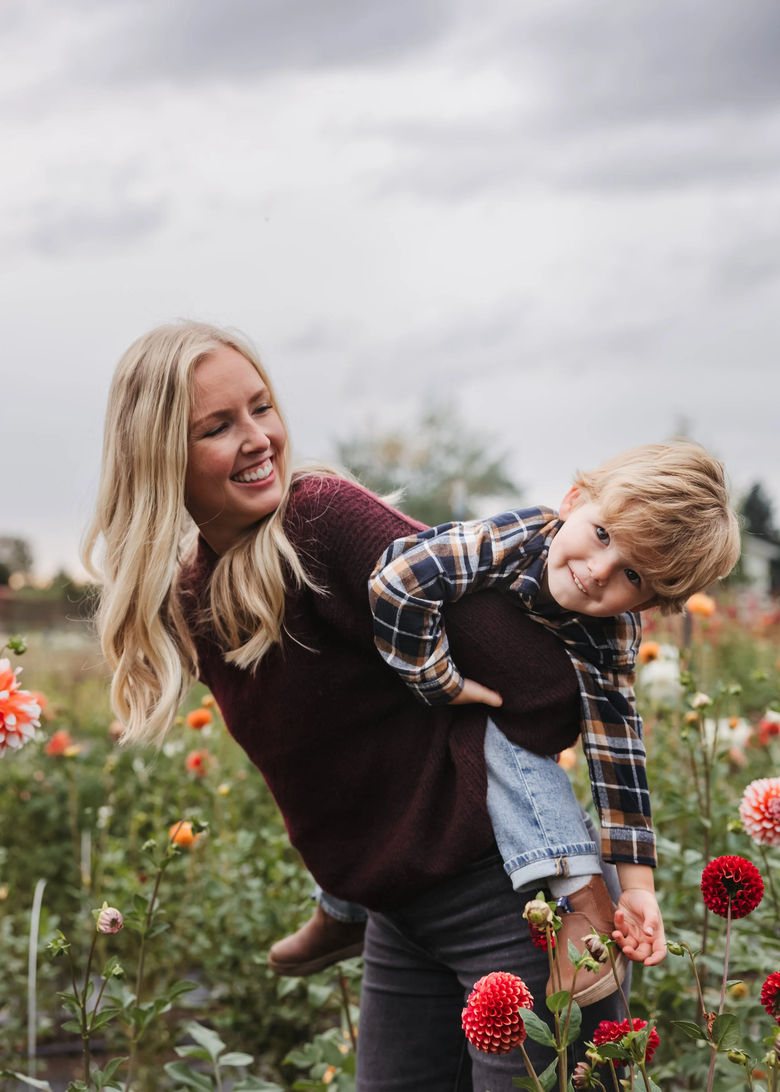 Young child with thoughtful expression held by mother surrounded by blooming flowers