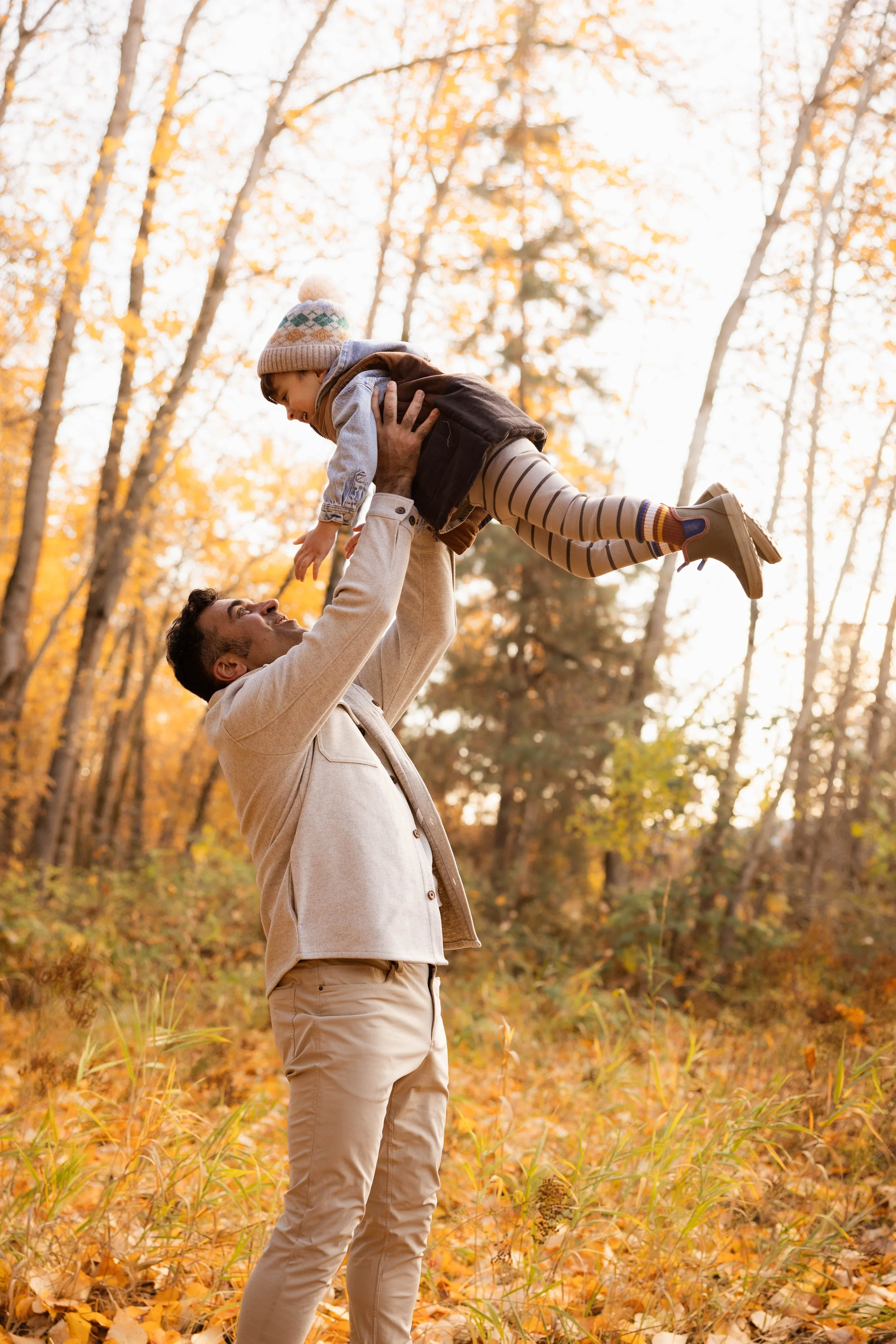 Smiling toddler holding both parents' hands during a playful family photography session in Coeur d'Alene.