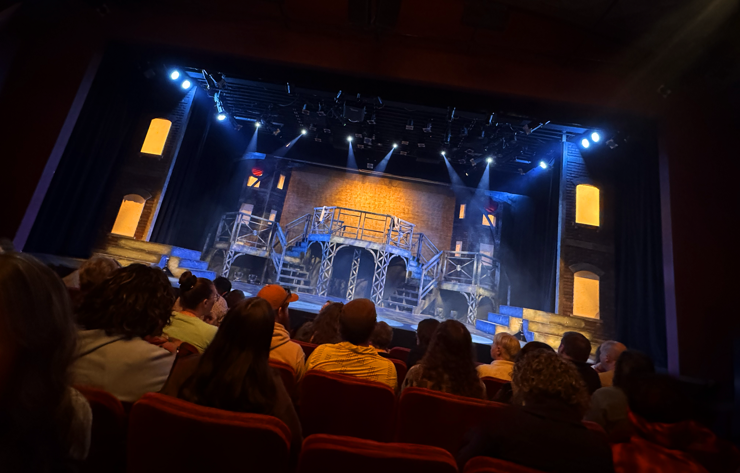 Theatre set design for the 2024 production of Newsies Jr. at Studio 410, featuring a multi-level industrial stage platform and scenic lighting, designed by Creativesphere.