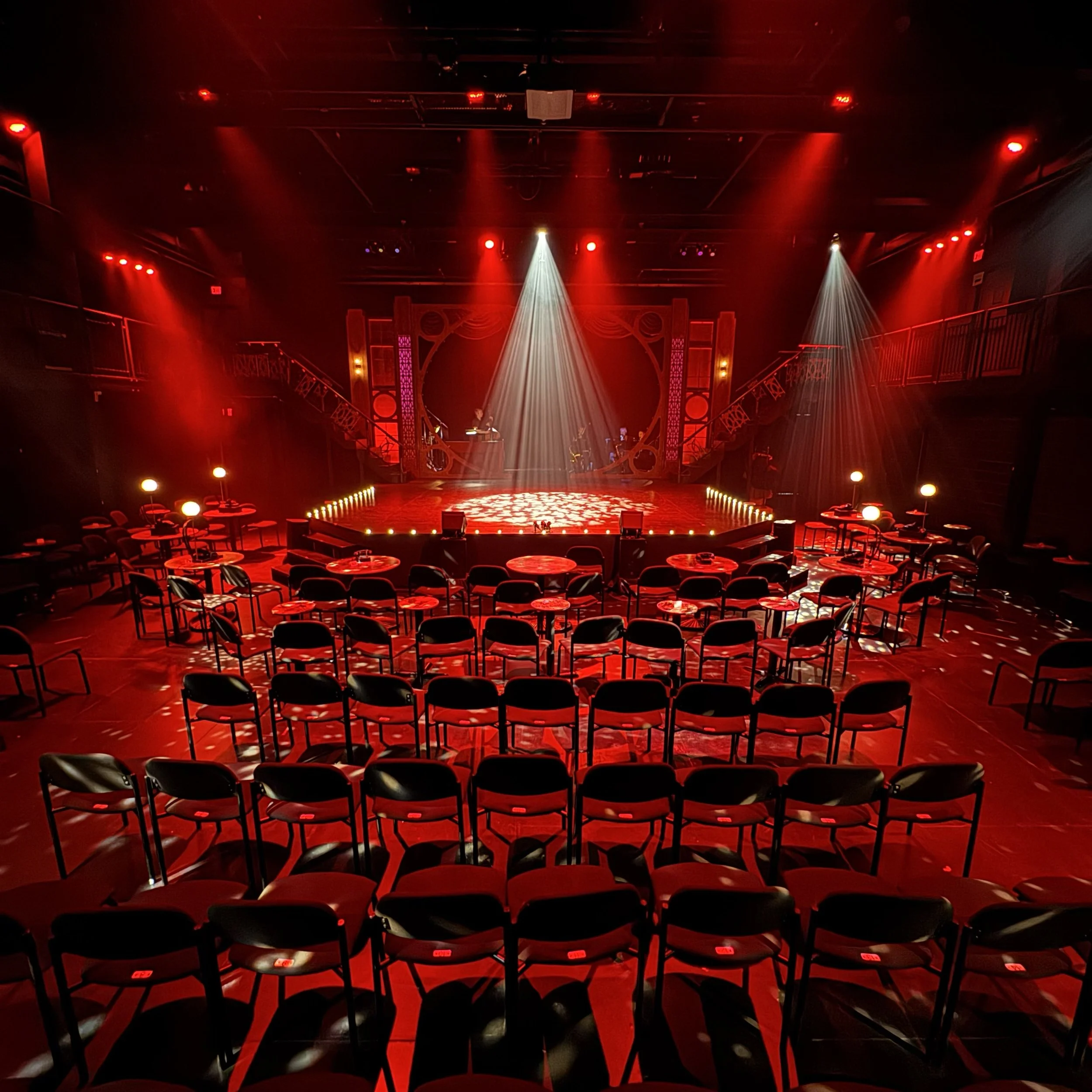 Immersive Cabaret theatre set design featuring a raised central stage, visible onstage band, multi-level platforms, and club-style audience seating surrounding the performance space, designed by Creativesphere.